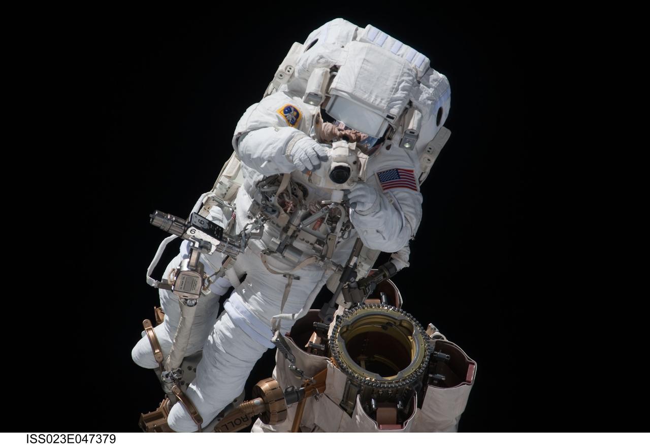 ISS023-E-047379 (17 May 2010) --- Anchored to a Canadarm2 mobile foot restraint, NASA astronaut Garrett Reisman, STS-132 mission specialist, uses a still camera during the mission's first session of extravehicular activity (EVA) as construction and maintenance continue on the International Space Station. During the seven-hour, 25-minute spacewalk, Reisman and NASA astronaut Steve Bowen (out of frame), mission specialist, loosened bolts holding six replacement batteries, installed a second antenna for high-speed Ku-band transmissions and adding a spare parts platform to Dextre, a two-armed extension for the station?s robotic arm.