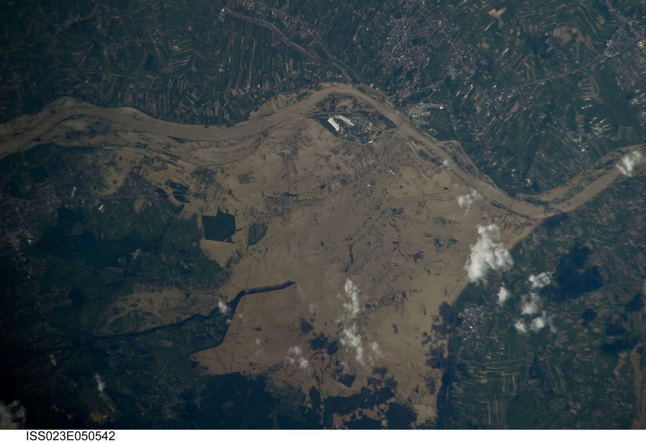ISS023-E-050542 (22 May 2010) --- Widespread flooding along the Vistula River in southeastern Poland is featured in this image photographed by an Expedition 23 crew member on the International Space Station. The Vistula River is a major river in Poland that originates in the western part of the Carpathian Mountains (specifically the western slopes of the mountain Barania Gora) in southern Poland. The river winds its way northward for 1,047 kilometers, through major cities such as Krakow and Warsaw, to Gdansk Bay on the Baltic Sea. Several towns have been completely or partially inundated including Gorzyce, Sokolniki and Trzesn in addition to large numbers of agricultural fields (normally green as visible at top and bottom right). While the flooding illustrated here is extensive, it represents but a small “snapshot” of conditions that have developed in Eastern Europe over the past two weeks. Spring flooding of rivers is not an uncommon occurrence in Poland but this event is being called the most serious flood in several decades. Severe floods were recorded in 1570, 1584, 1719, 1891, and 1997, with the first records of local embankments for flood control dating from the thirteenth century. By 1985, 370 rivers in Poland (including the Vistula) had been completely or partly embanked along a total length of 9,028 kilometers for some degree of flood mitigation. Heavy rains caused high waters in the Vistula River first in southern Poland. Hundreds of thousands of people were evacuated as the river level rose and broke through water-logged dikes and embankments. The flood surge then moved northward through Warsaw and continues towards the Baltic Sea.
