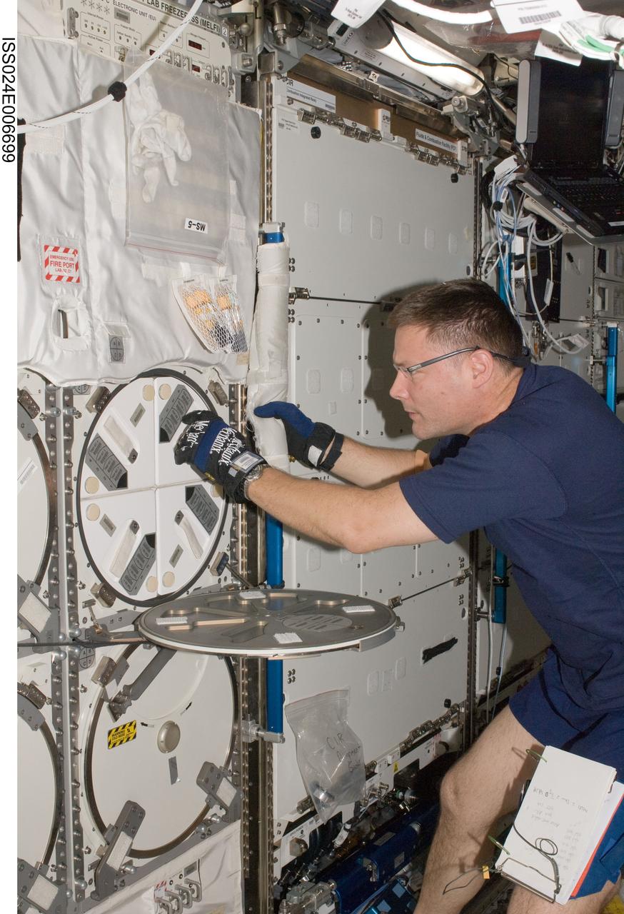 ISS024-E-006699 (28 June 2010) --- NASA astronaut Doug Wheelock, Expedition 24 flight engineer, prepares to insert biological samples into trays in the Minus Eighty Laboratory Freezer for ISS-2 (MELFI-2) in the Destiny laboratory of the International Space Station.