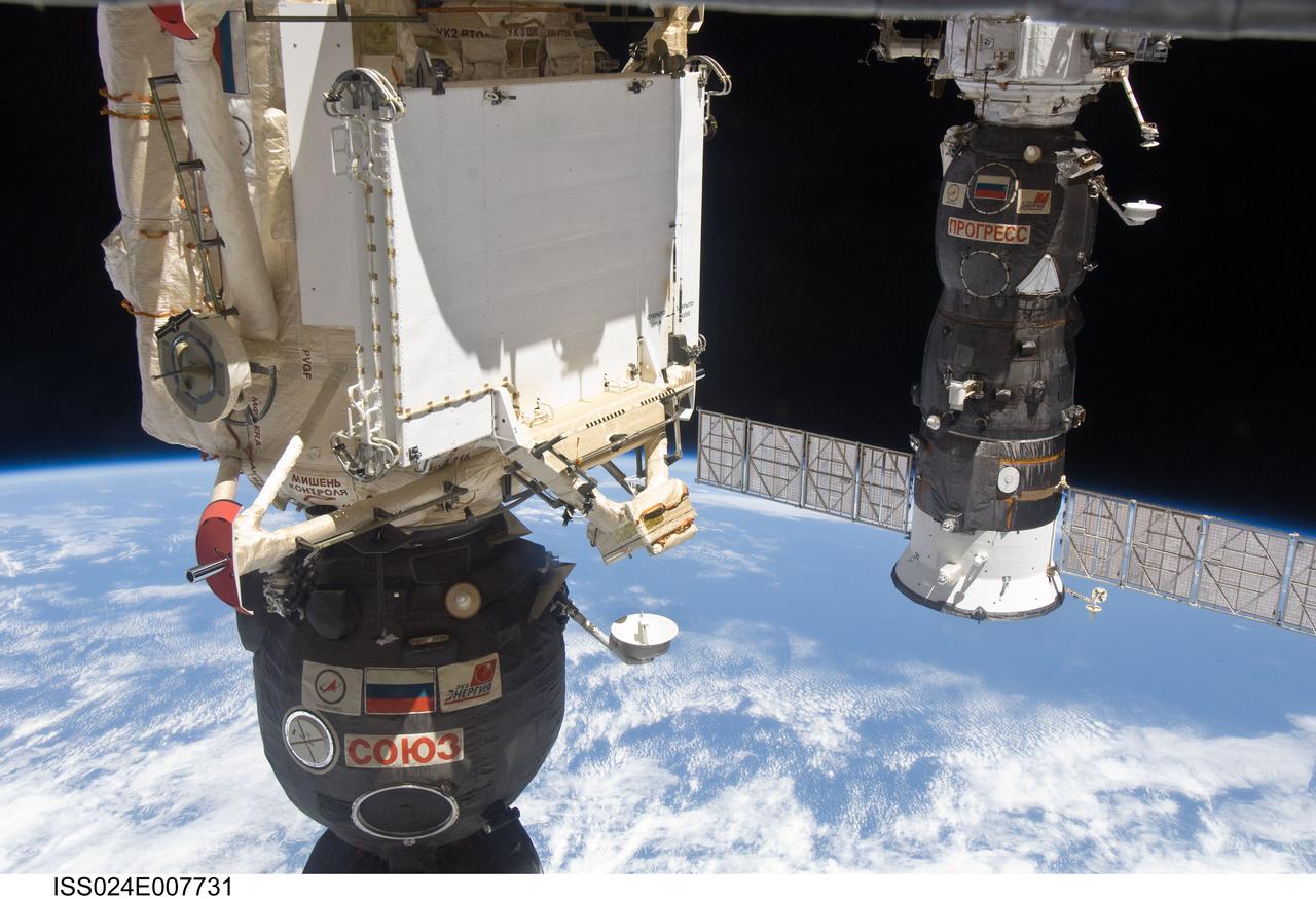 ISS024-E-007731 (9 July 2010) --- The Soyuz TMA-19 spacecraft (partially out of frame in the foreground), docked to the Rassvet Mini-Research Module 1 (MRM1), and Progress 37 resupply vehicle, docked to the Pirs Docking Compartment, are featured in this image photographed by an Expedition 24 crew member on the International Space Station. A blue and white part of Earth and the blackness of space provide the backdrop for the scene.