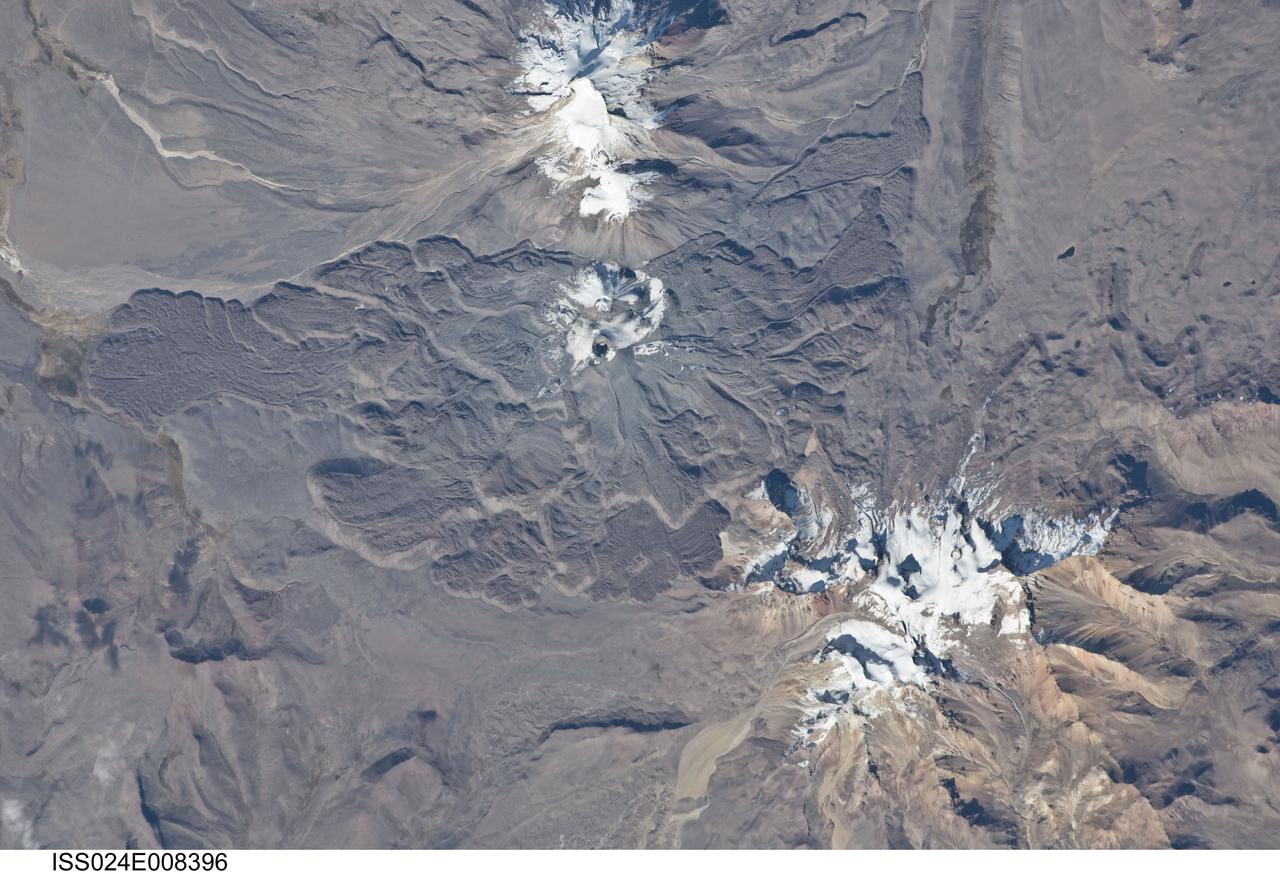 ISS024-E-008396 (15 July 2010) --- Sabancaya volcano in Peru is featured in this image photographed by an Expedition 24 crew member on the International Space Station. The 5,967-meter-high Sabancaya stratovolcano (or Nevado Sabancaya) is located in southern Peru approximately 70 kilometers to the northwest of the city of Arequipa. The name Sabancaya means ?tongue of fire? in the Quechua Indian language. Sabancaya is part of a volcanic complex that includes two other nearby (and older) volcanoes, neither of which has been active historically; in this detailed photograph, Nevado Ampato is visible to the south (top center) and the lower flanks of Nevado Hualca Hualca are visible to the north (bottom right). The snowy peaks of the three volcanoes provide a stark contrast to the surrounding desert of the Puna Plateau. Sabancaya?s first historical record of an eruption dates to 1750. The most recent eruptive activity at the volcano occurred in July 2003 and deposited ash on the volcano?s summit and northeastern flank. Volcanism at Sabancaya is fueled by magma generated at the subduction zone between the Nazca and South American tectonic plates.  Magma can erupt to the surface and form lava flows through the volcano?s summit (frequently forming a crater) but can also erupt from lava domes and flank vents along the volcano?s sides. Lava has issued from all of these points at Sabancaya, forming numerous gray to dark brown lobate flows that extend in all directions except southwards (center).