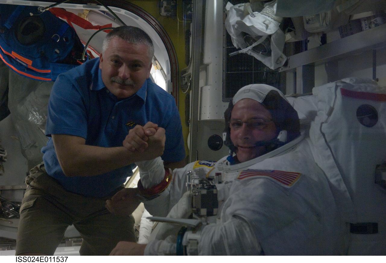 ISS024-E-011537 (7 Aug. 2010) --- NASA astronaut Doug Wheelock (right), attired in his Extravehicular Mobility Unit (EMU) spacesuit, and Russian cosmonaut Fyodor Yurchikhin, both Expedition 24 flight engineers, pose for a photo in the Quest airlock of the International Space Station during preparations for the first of three planned spacewalks to remove and replace an ammonia pump module that failed July 31.
