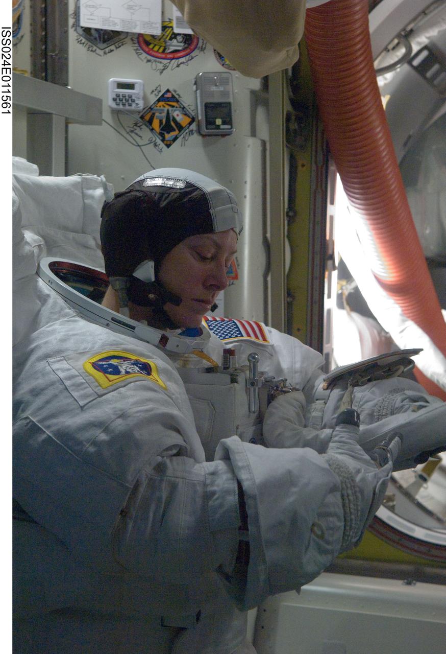 ISS024-E-011561 (7 Aug. 2010) --- NASA astronaut Tracy Caldwell Dyson, Expedition 24 flight engineer, dons her Extravehicular Mobility Unit (EMU) spacesuit in the Quest airlock of the International Space Station in preparation for the first of three planned spacewalks to remove and replace an ammonia pump module that failed July 31.