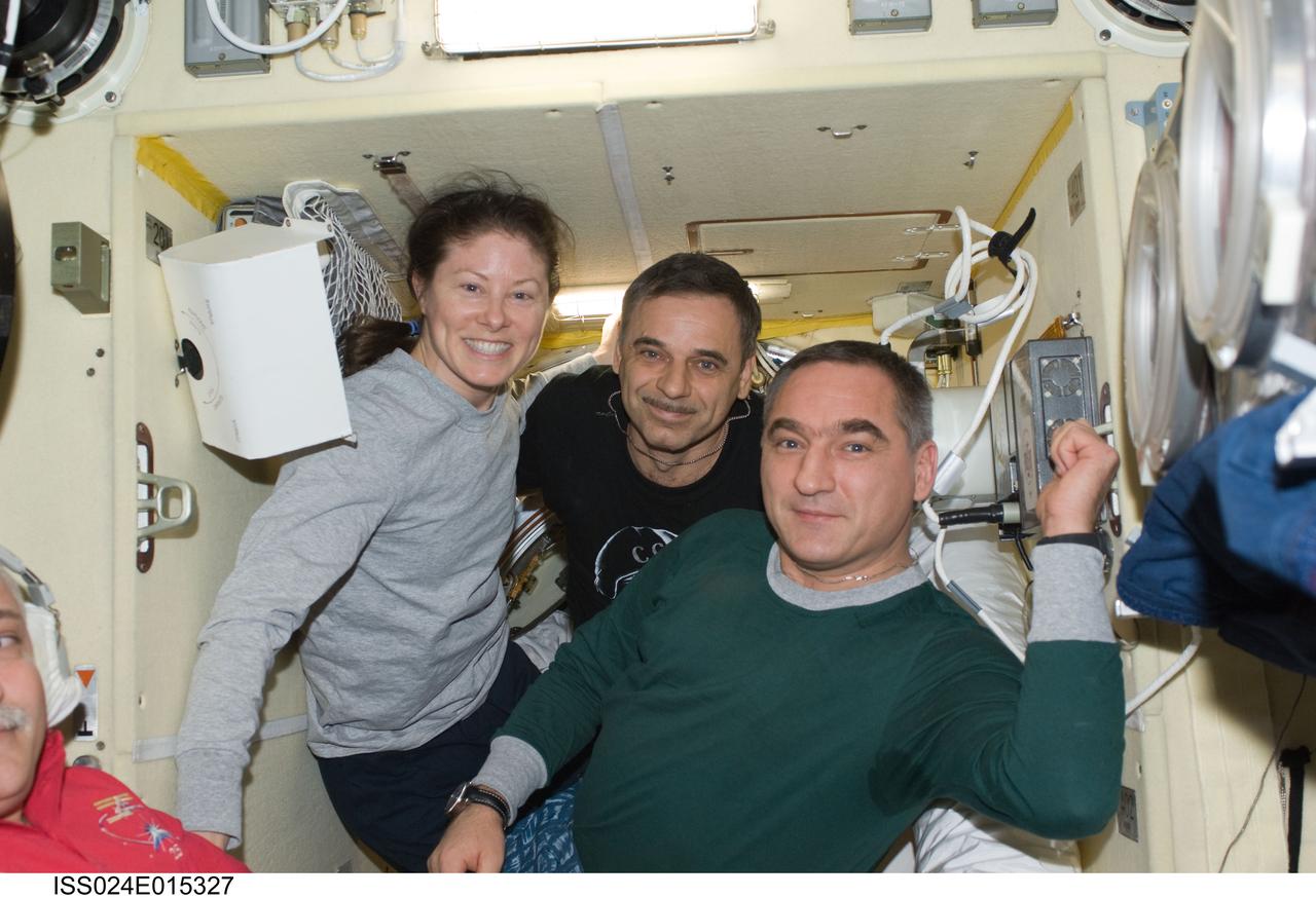 ISS024-E-015327 (24 Sept. 2010) --- Russian cosmonaut Alexander Skvortsov (right), Expedition 24 commander; NASA astronaut Tracy Caldwell Dyson and Russian cosmonaut Mikhail Kornienko, both flight engineers, pose for a photo during final preparations for their departure in the Soyuz TMA-18 docked to the Poisk Mini-Research Module 2 (MRM2) of the International Space Station. Originally scheduled for Sept. 23, the Soyuz undocked a day later due to a Poisk-side hatch sensor problem, which prevented hooks on the Poisk side of the docking interface from opening. The Soyuz undocked at 10:02 p.m. (EDT) on Sept. 24, 2010.