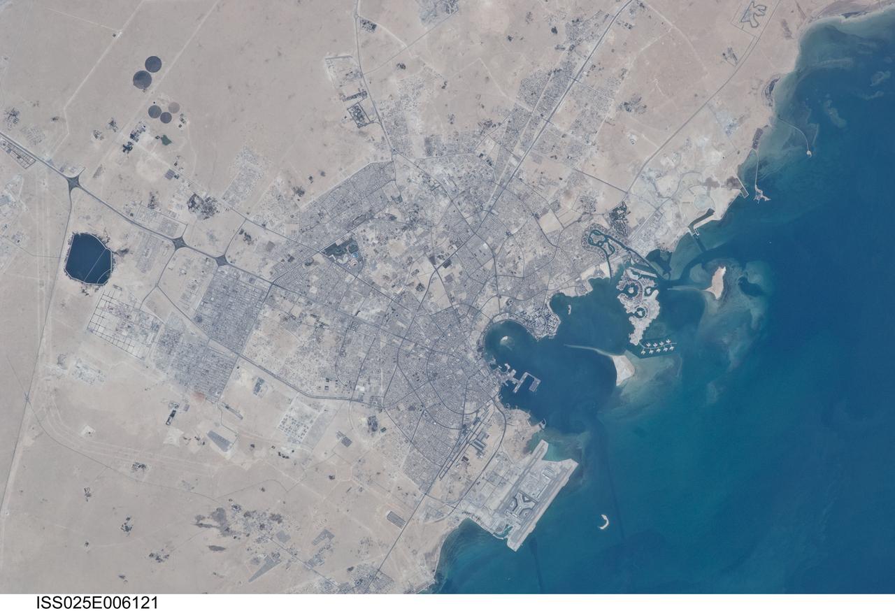 ISS025-E-006121 (5 Oct. 2010) --- Doha City, Doha Bay, State of Qatar and the Persian Gulf are featured in this image photographed by an Expedition 25 crew member on the International Space Station. The old and new zones of Doha, the capital city of the Persian Gulf state of Qatar, are visible in this photograph. The old city comprises the ancient bazaar, or Souq, near the dhow harbor (a dhow is a traditional Arab sailing vessel) which is still used today. Subsequent developments have taken place progressively further from the ancient center, with successive ring roads concentrically arranged around it. Modern port facilities can be seen immediately to the east of the Souq. The diplomatic quarter is reached via the Corniche promenade north of the old city. Yet further away an extensive marina complex known as West Bay Lagoon, with boating access to the Persian Gulf, stands out. Qatar’s new artificial island, known as the Pearl-Qatar, is under construction with 32 kilometers of new coastline, just offshore of West Bay Lagoon. This vast development is intended mainly as a residential zone with themes based on Arabic, Mediterranean and European cultures. The Pearl-Qatar complex is named for the fact that the new island is being built on one of Qatar’s major historical pearl diving sites. A string of small islands built along the outer margin of the complex is intended to recall the pearl-diving culture of the nation’s past.