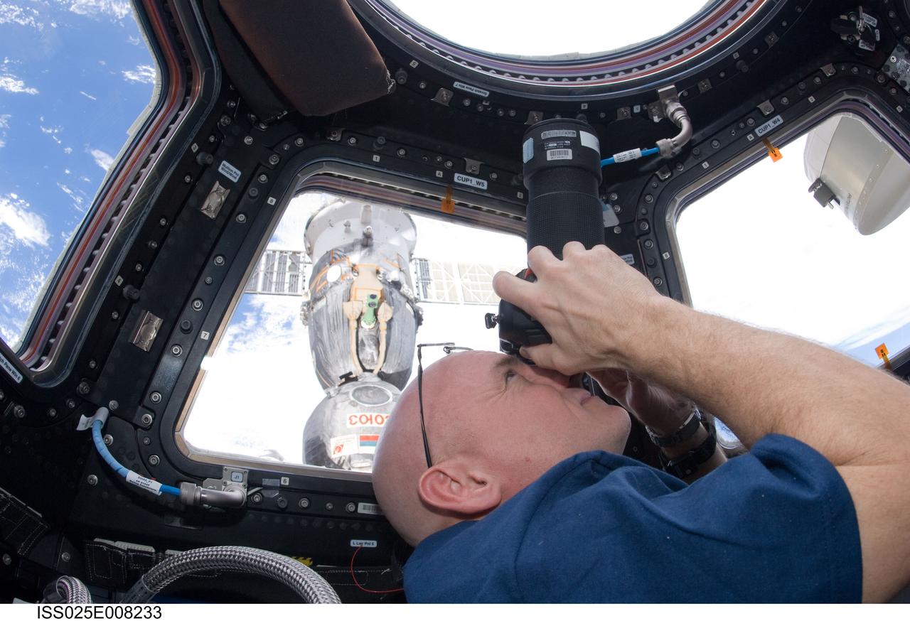 ISS025-E-008233 (19 Oct. 2010) --- NASA astronaut Scott Kelly, Expedition 25 flight engineer, uses a still camera to photograph the topography of a point on Earth from a window in the Cupola of the International Space Station.