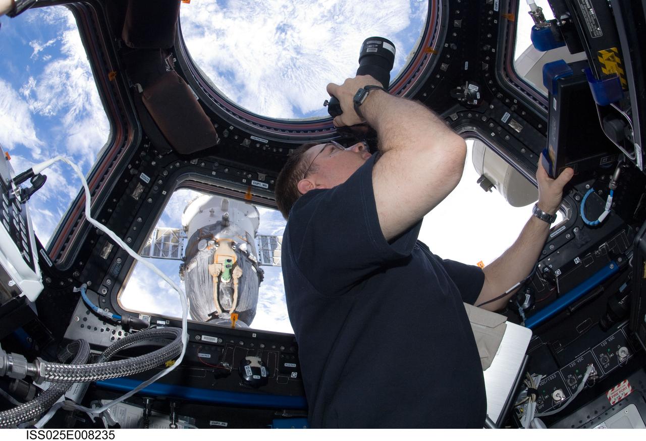 ISS025-E-008235 (19 Oct. 2010) --- NASA astronaut Doug Wheelock, Expedition 25 commander, uses a still camera to photograph the topography of a point on Earth from a window in the Cupola of the International Space Station.