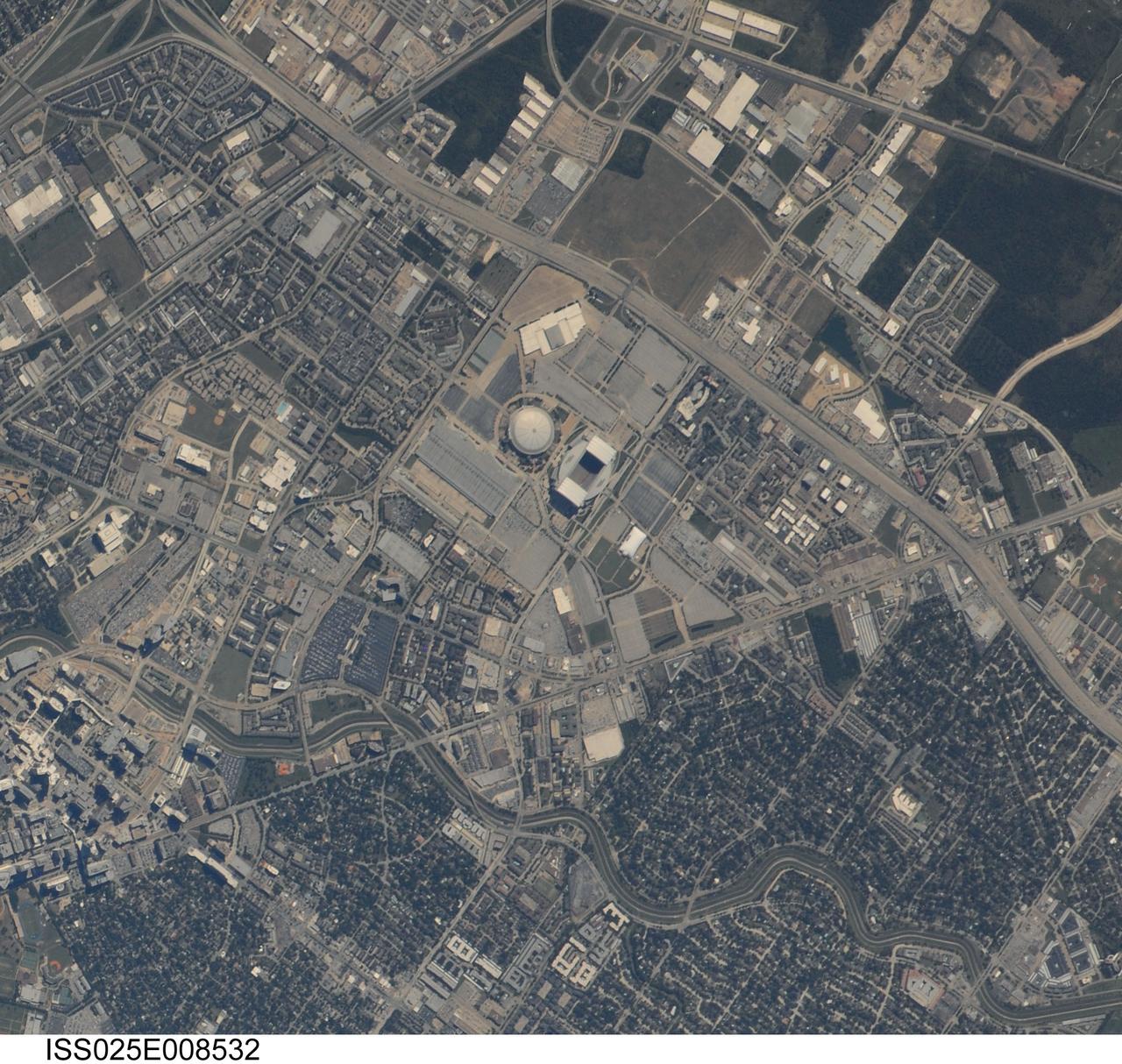 ISS025-E-008532 (5 Oct. 2010) --- Photographed by an Expedition 25 crew member on the International Space Station, this highly detailed photograph highlights the Reliant Park area of the Houston, TX “inner loop”, defined as that part of the metropolitan area located within Interstate Highway 610 that rings the downtown area. Reliant Park includes two large sports complexes visible at center, Reliant Stadium and Reliant Astrodome. Houston is the location of the NASA Johnson Space Center (out of frame) and is notable among major US metropolitan areas for its lack of formal zoning ordinances (other forms of regulation play a similar role here). This leads to highly mixed land use within the urban and suburban areas of the city. The land uses adjacent to Reliant Park include large asphalt parking areas, vacant lots with a mixture of green grass cover and brown exposed topsoil, and both single- and multi-family residential areas. A forested area (dark green, lower left) is located less than two kilometers from the parking lots of Reliant Park. This subset of a handheld digital camera image has a spatial resolution of 2-3 meters per pixel (or picture element), making it one of the highest spatial resolution images yet obtained from the space station. Such high image resolution is made possible by using lens “doublers” to increase the optical magnification of camera lenses. As important is active ISS motion compensation by experienced astronauts during photography. Motion compensation requires the astronaut to pan the camera by hand at just the right rate, keeping the object at the same point in the viewfinder. The technique involves bracing oneself against the space station bulkhead to prevent movement related to weightlessness. Early attempts produce a “smeared” image that looks out of focus. Traditional short lens photography is easier because it does not require motion compensation.
