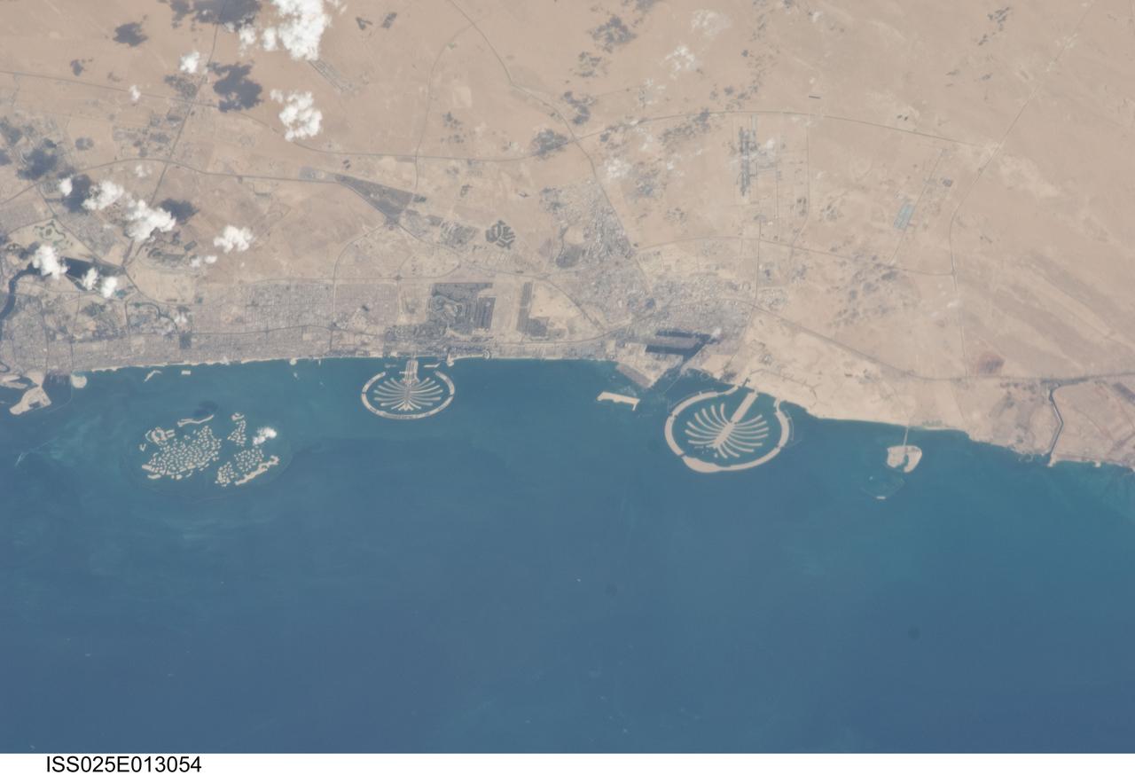 ISS025-E-013054 (7 Nov. 2010) --- Man-made archipelagos near Dubai, United Arab Emirates, are featured in this image photographed by an Expedition 25 crew member on the International Space Station, flying at 220 miles above Earth. The municipality of Dubai is the largest city of the Persian Gulf emirate of the same name, and has built a global reputation for large-scale developments and architectural works. Among the most visible of these developments -- particularly from the perspective of astronauts onboard the ISS -- are three man-made archipelagos. The two Palm Islands -- Palm Jumeirah to the left of center, and Palm Jebel Ali, just to the right of center,  appear as stylized palm trees when viewed from above. The World Islands  (near left edge) evoke a rough map of the world from an air- or space-borne perspective. The Palm Jumeirah project began in 2001 and required more than 50 million cubic meters of dredged sand to raise the islands above the Persian Gulf sea level. Construction of the Palm Jumeirah islands was completed in 2006; they are now being developed for residential and commercial housing and infrastructure. Creation of the World Islands was begun in 2003 and completed in 2008, using 320 million cubic meters of sand and 37 million tons of rock for the surrounding 27 kilometer-long protective breakwater.