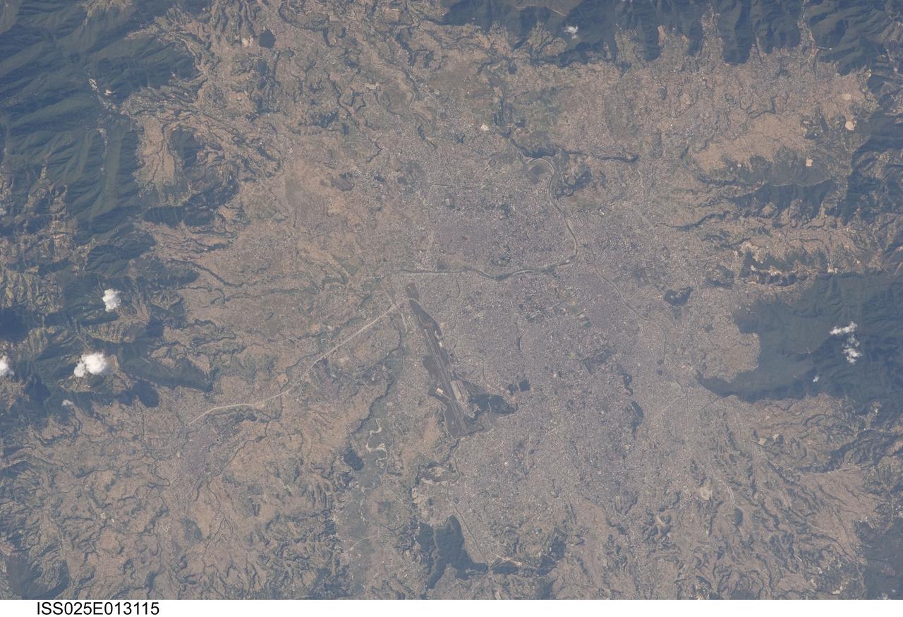 ISS025-E-013115 (9 Nov. 2010) --- Kathmandu, Nepal is featured in this image photographed by an Expedition 25 crew member on the International Space Station. The capital and largest city of Nepal, Kathmandu occupies much of the Kathmandu Valley located near the center of the country. Nepal itself contains much of the Himalaya mountain range between China (Tibet) to the north and India to the south. Geological and fossil evidence indicates that the Kathmandu Valley was filled by a large lake (Paleo-Kathmandu Lake) between approximately 2.8 million and 10,000 years ago, according to scientists. Geologists believe the lake drained in phases over time due both to a drier regional climate, continuing tectonic uplift and faulting in the region, and formation of an integrated valley drainage system as river channels cut through previous natural rock ridge dams. The green vegetated slopes that ring the Kathmandu metro area (light gray, center) include both forest reserves and national parks. The metropolitan area is relatively flat compared to the surrounding high mountains. Tribhuvan International Airport, located near the current eastern margin of the metro area, is the only international airport in Nepal. Archeological evidence suggests that the development of Kathmandu, together with the nearby “sister cities” of Lalitpur and Bhaktapur, began almost 2,000 years ago. Today, Kathmandu and its sister cities form the governmental, cultural, and—as a main access point to the Himalayas for tourism—economic center of the country.
