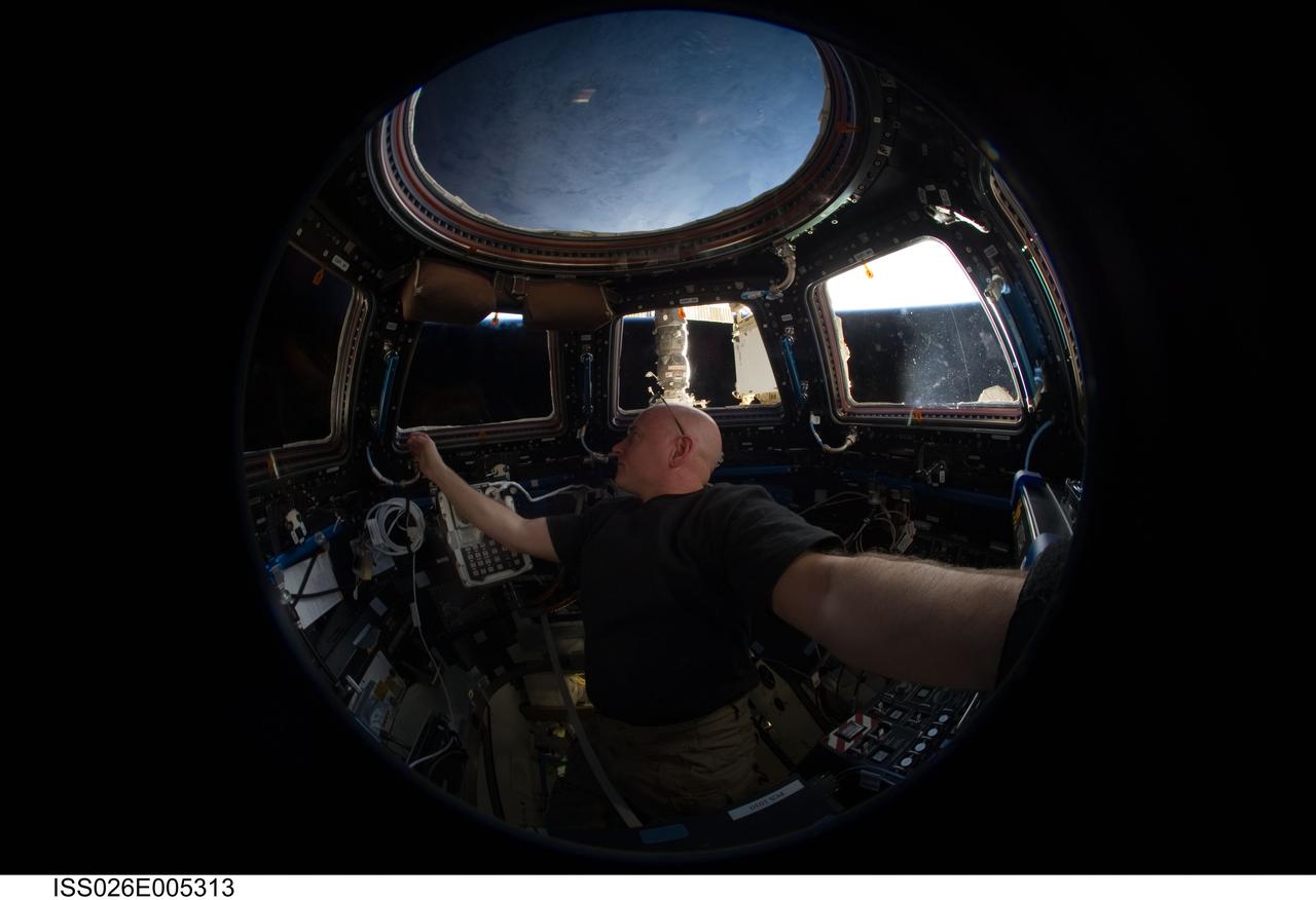 ISS026-E-005313 (26 Nov. 2010) --- A fish-eye lens attached to an electronic still camera was used to capture this image of NASA astronaut Scott Kelly, Expedition 26 commander, in the Cupola of the International Space Station.