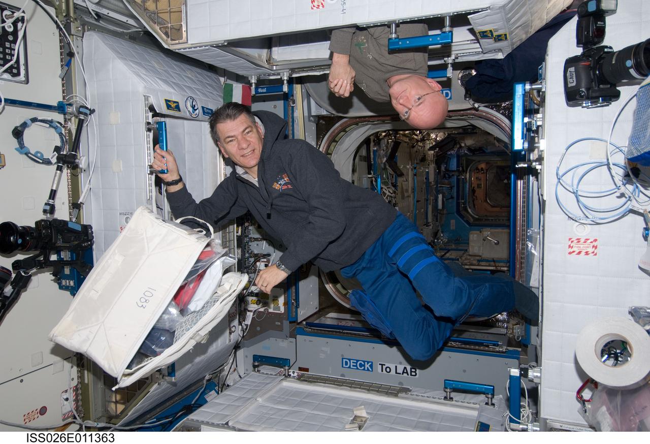 ISS026-E-011363 (19 Dec. 2010) --- NASA astronaut Scott Kelly (top), Expedition 26 commander; and European Space Agency astronaut Paolo Nespoli, flight engineer, are pictured at their crew quarters compartments in the Harmony node of the International Space Station.