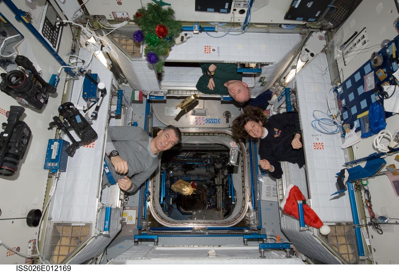 ISS026-E-012169 (25 Dec. 2010) --- Three of the six crew members aboard the International Space Station peek out of their sleeping quarters on Christmas morning to view the station?s decorations and gifts. Shown, from left, are European Space Agency astronaut Paolo Nespoli, Expedition 26 flight engineer, NASA astronaut Scott Kelly, Expedition 26 commander, and NASA astronaut Catherine (Cady) Coleman, flight engineer.