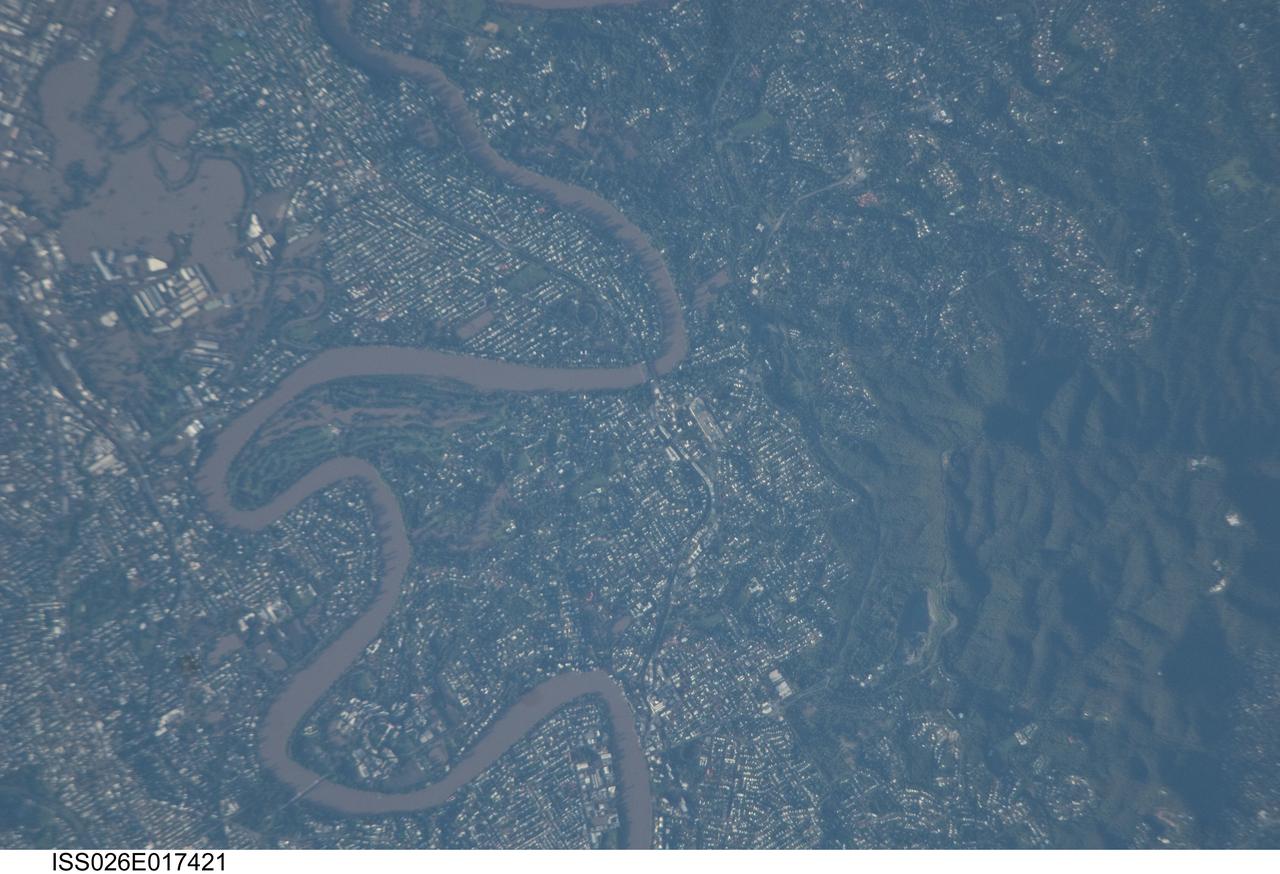 ISS026-E-017421 (13 Jan. 2011) --- Photographed by an Expedition 26 crew member on the International Space Station, this detailed photograph illustrates flooding in suburbs of the Brisbane, Australia metropolitan region. The Brisbane area experienced catastrophic flooding following unusually heavy rainfall on Jan. 10, 2011. With surficial soils already saturated from previous rainfall events, eastward-draining surface flow caused the Brisbane River to flood—inundating an estimated 20,000 homes in suburbs of the capital city of Queensland. Other cities in Queensland have also experienced damaging floods during previous heavy rainfall events this year. The image highlights several suburbs along the Brisbane River in the southern part of the Brisbane metropolitan area. The light-colored rooftops of residences and other structures contrast sharply with green vegetation and brown, sediment laden floodwaters. Most visible low-lying areas are inundated by floodwater, perhaps the most striking being Rocklea at upper left. The suburb of Yeronga (lower left) also has evident regions of flooding, as does a park and golf course located along a bend in the Brisbane River to the south of St. Lucia (center). Flooding becomes less apparent near the higher elevations of Mt. Coot-Tha at right.