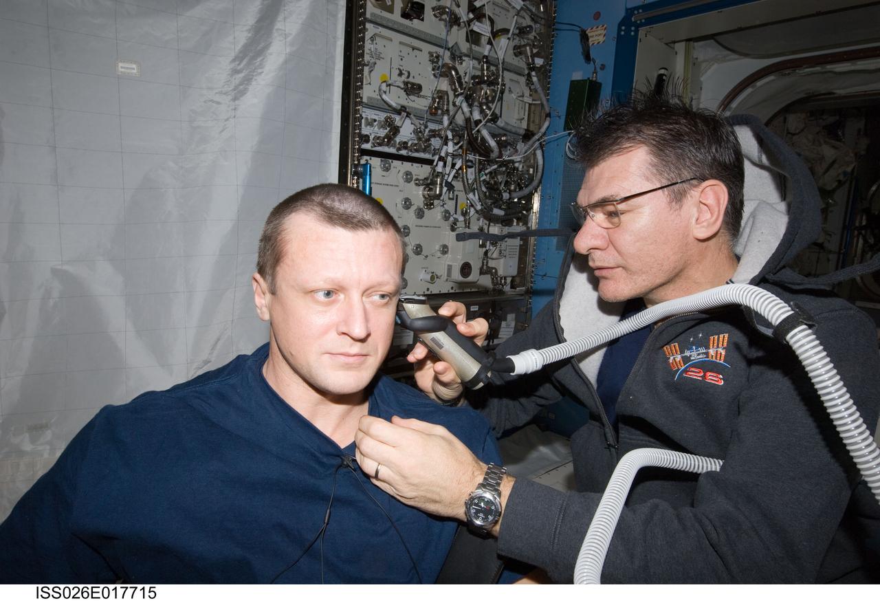 ISS026-E-017715 (15 Jan. 2011) --- European Space Agency astronaut Paolo Nespoli assists cosmonaut Dmitry Kondratyev of Russia's Federal Space Agency (Roscosmos) with a haircut in the Kibo laboratory on the International Space Station. The two Expedition 26 flight engineers used a vacuum cleaner to remove free-floating hair particles from the air.