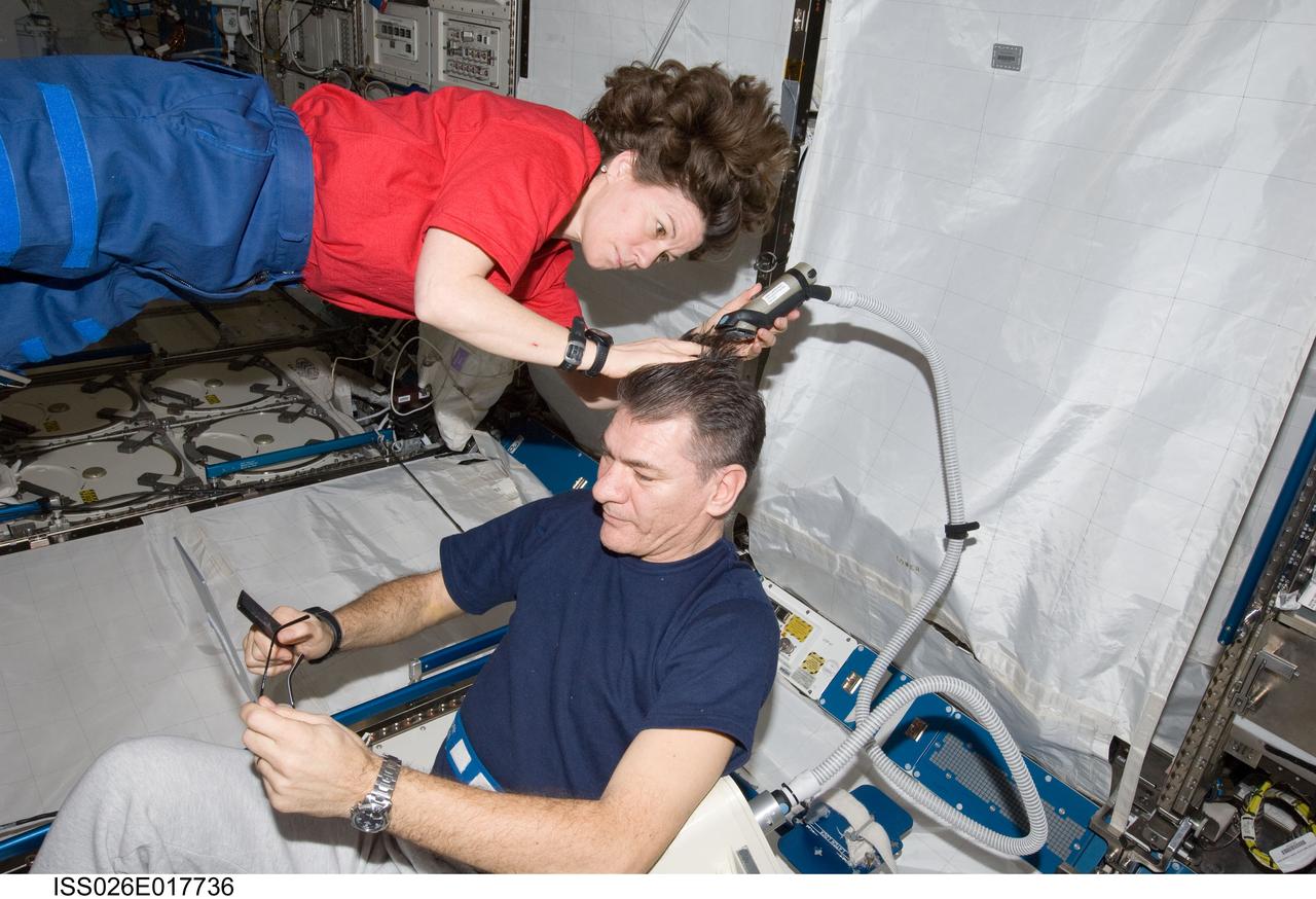 ISS026-E-017736 (15 Jan. 2011) --- NASA astronaut Catherine (Cady) Coleman assists European Space Agency astronaut Paolo Nespoli with a haircut in the Kibo laboratory on the International Space Station. The two Expedition 26 flight engineers used a vacuum cleaner (partially out of frame) to remove free-floating hair particles from the air.