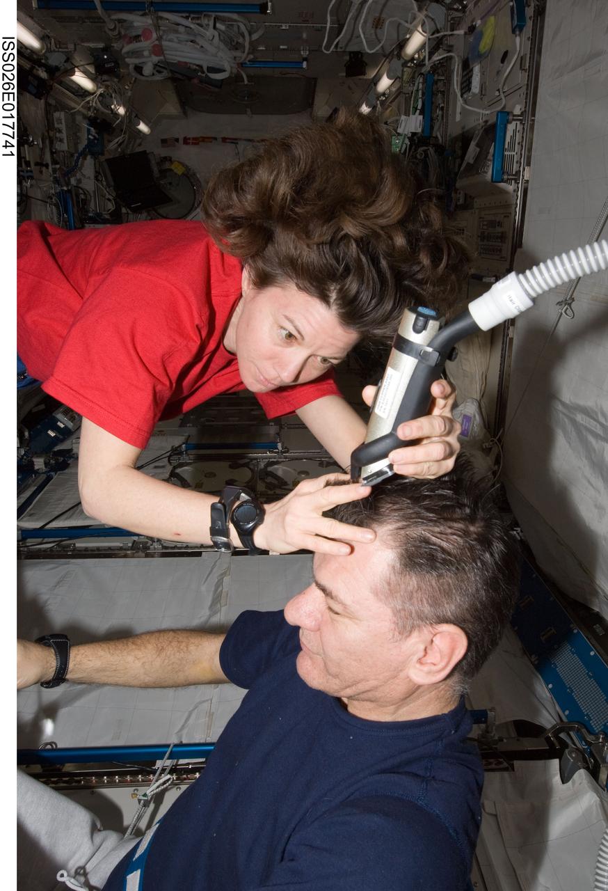 ISS026-E-017741 (15 Jan. 2011) --- NASA astronaut Catherine (Cady) Coleman assists European Space Agency astronaut Paolo Nespoli with a haircut in the Kibo laboratory on the International Space Station. The two Expedition 26 flight engineers used a vacuum cleaner (partially out of frame) to remove free-floating hair particles from the air.