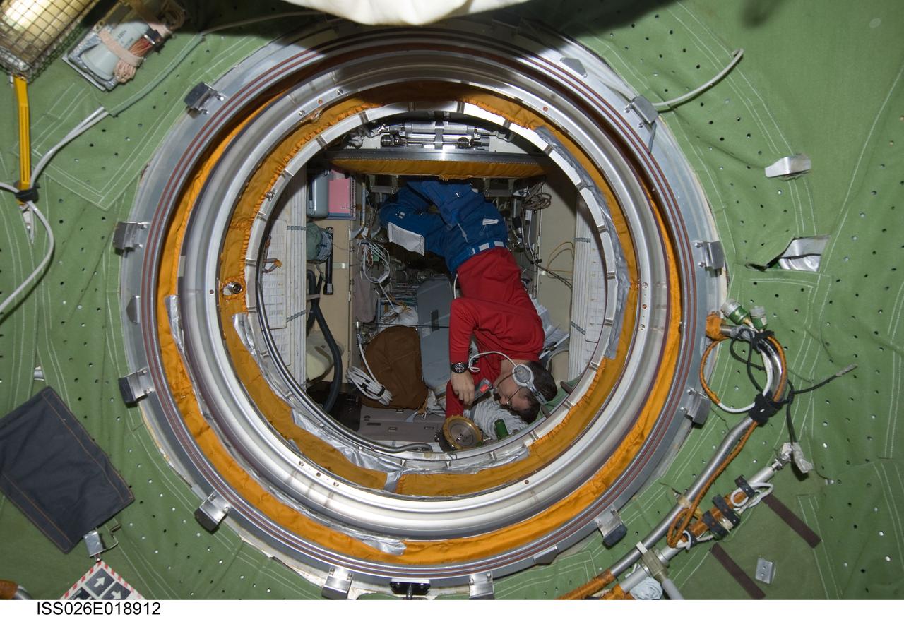 ISS026-E-018912 (21 Jan. 2011) --- While wearing a communication system headset, European Space Agency astronaut Paolo Nespoli, Expedition 26 flight engineer, uses a flashlight while checking an Absolute Pressure gauge in the Zarya Functional Cargo Block (FGB) of the International Space Station.