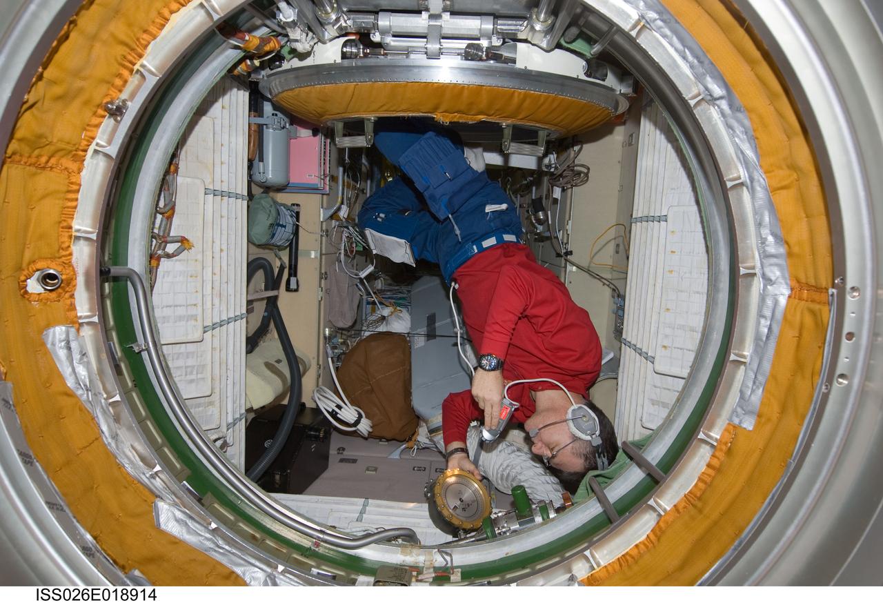 ISS026-E-018914 (21 Jan. 2011) --- While wearing a communication system headset, European Space Agency astronaut Paolo Nespoli, Expedition 26 flight engineer, uses a flashlight while checking an Absolute Pressure gauge in the Zarya Functional Cargo Block (FGB) of the International Space Station.