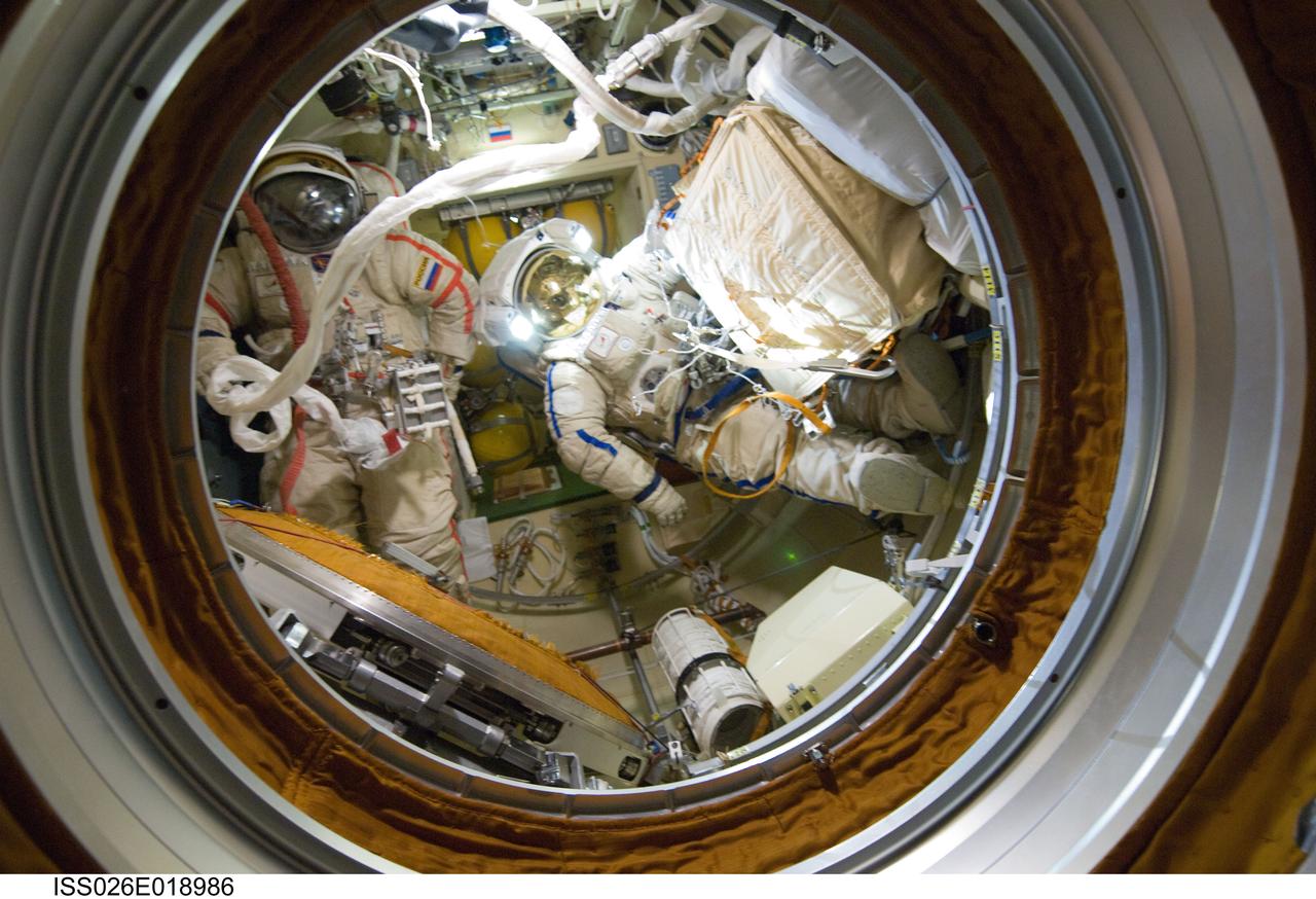 ISS026-E-018986 (21 Jan. 2011) --- Attired in their Russian Orlan spacesuits, Russian cosmonauts Dmitry Kondratyev (left) and Oleg Skripochka, both Expedition 26 flight engineers, are pictured in the Pirs Docking Compartment of the International Space Station as their session of extravehicular activity (EVA) draws to a close.