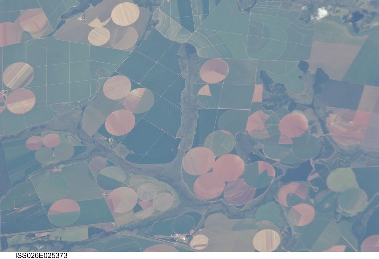 ISS026-E-025373 (10 Feb. 2011) --- Agricultural fields near Perdizes, Minas Gerais, Brazil are featured in this image photographed by an Expedition 26 crew member on the International Space Station. This detailed photograph illustrates diverse agricultural landscape patterns in the western part of the Brazilian State of Minas Gerais. Perhaps most widely known for its mineral wealth, Minas Gerais is also a large agricultural producer in Brazil. The fields in the image are located to the southwest of the city of Perdizes, which means “partridges” in Portuguese. A mix of regularly-gridded polygonal fields, and circular center-pivot fields, marks the human land use of the region. Small tributary streams (and their adjacent floodplains) of the Araguari River extend like fingers throughout the agricultural landscape. The visual diversity of field forms is matched by the variety of crops produced here: sunflowers, wheat, potatoes, coffee, rice, soybeans, and corn are among the agricultural products of the region. While the Northern Hemisphere is still in the grip of winter, crops are growing in the Southern Hemisphere as indicated by the many green fields in the image. Fallow fields—fields not in active agricultural use—display the violet, reddish to light tan soils common to this part of Brazil. The darker soils are often rich in iron and aluminum oxides, and are typical of highly weathered soil material that forms in hot, humid climates.
