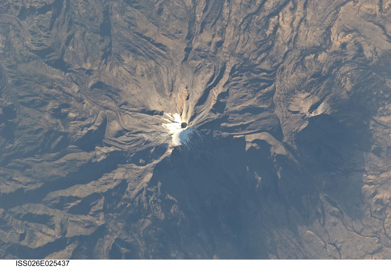 ISS026-E-025437 (10 Feb. 2011) --- Pico de Orizaba, Mexico is featured in this image photographed by an Expedition 26 crew member on the International Space Station. The snow and ice-clad peak of Pico de Orizaba (also known as Citlaltepetl) boasts a summit elevation of 5,675 meters (18,619 feet) above sea level, making it the highest peak in Mexico and North America’s highest volcano. It is also one of three volcanic peaks in Mexico—together with Popocatepetl and Iztaccihuatl—that retain summit glaciers. Pico de Orizaba is part of the Trans-Mexican Volcanic Belt that extends roughly east-west across Mexico. The last recorded eruption took place in 1846; while the volcano is considered dormant at present, geologists continue to investigate the potential hazards associated with a renewal of activity. Shadows accentuate several features of the Pico de Orizaba stratovolcano visible in this photograph from the space station. The 300-meter-deep summit crater is clearly visible against surrounding ice and snow cover at center. Several lava flows extend down the flanks of the volcano, made readily visible by prominent cooling ridges along their sides known as flow levees—one of the most clearly visible examples is located on the southwest flank of the cone. The extinct Sierra Negra volcano to the southwest has a summit elevation of 4,640 meters (15,223 feet) above sea level; while not as lofty as Pico de Orizaba, it is also one of Mexico’s highest peaks.
