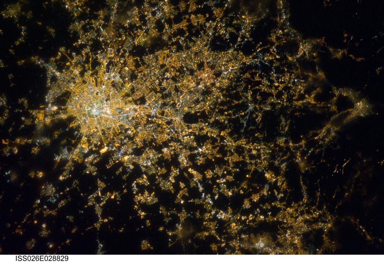 ISS026-E-028829 (22 Feb. 2011) --- Milan, Italy metropolitan area is featured in this night time view photographed by an Expedition 26 crew member on the International Space Station. The metropolitan area of Milan (or Milano) illuminates the Italian region of Lombardy, in a pattern evocative of a patchwork quilt, in this photograph. The city of Milan proper forms a dense cluster of lights at center left; brilliant white lights indicate the historic center of the city where the Duomo di Milano (Milan Cathedral) is located. Large dark regions to the south of Milan contain mostly agricultural fields. To the north, numerous smaller cities are interspersed with agricultural fields giving way to forested areas as one approaches the Italian Alps (not shown). Low patchy clouds diffuse the city lights, producing isolated regions in the image that appear blurred. The Milan urban area is located within the Po Valley, a large plain bordered by the Adriatic Sea to the south and the Italian Alps to the north. Milan has the largest metropolitan area in Italy, and the fifth largest in the European Union.