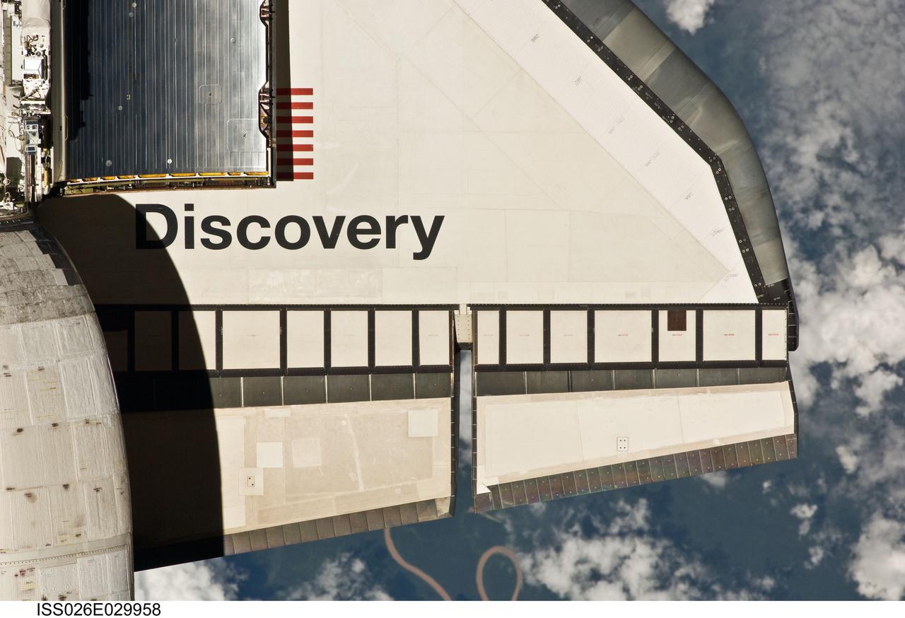 ISS026-E-029958 (26 Feb. 2011) --- This partial view of the starboard wing of the space shuttle Discovery was provided by an Expedition 26 crew member during a survey of the approaching STS-133 vehicle prior to docking with the International Space Station. As part of the survey and part of every mission's activities, Discovery performed a back-flip for the rendezvous pitch maneuver (RPM). The image was photographed with a digital still camera, using a 400mm lens at a distance of about 600 feet (180 meters). Although at first glance, it appears there is some sort of wire or cord hanging from the shuttle, the curly object is actually 220 miles below and appears to be a portion of the Alto Purus River in southeastern Peru near the village of San Pedro in Ucayali province.