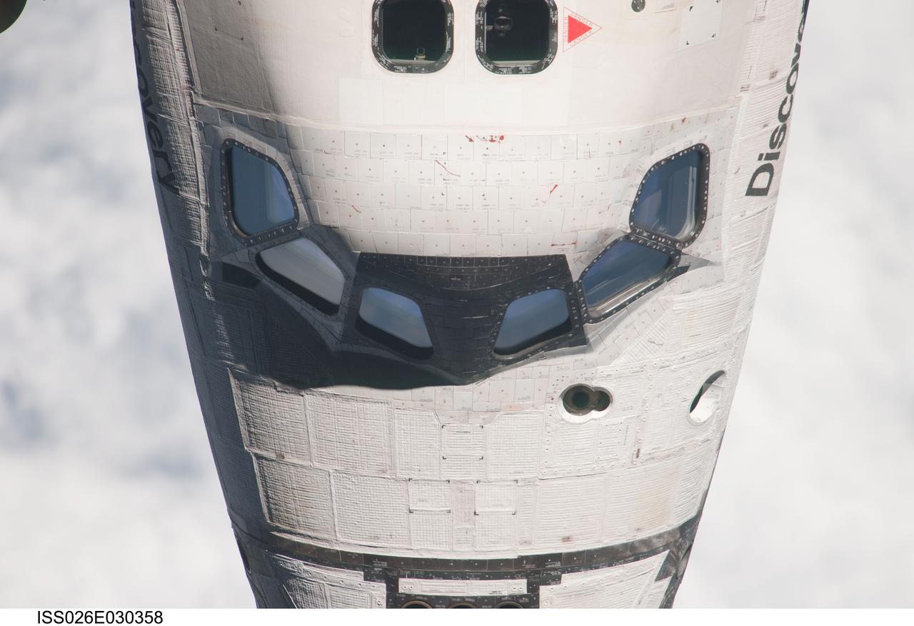 ISS026-E-030358 (26 Feb. 2011) --- This partial view of the nose and crew cabin of the space shuttle Discovery was provided by an Expedition 26 crew member during a survey of the approaching STS-133 vehicle prior to docking with the International Space Station. As part of the survey and part of every mission's activities, Discovery performed a back-flip for the rendezvous pitch maneuver (RPM).  The image was photographed with a digital still camera, using a 1000mm lens.