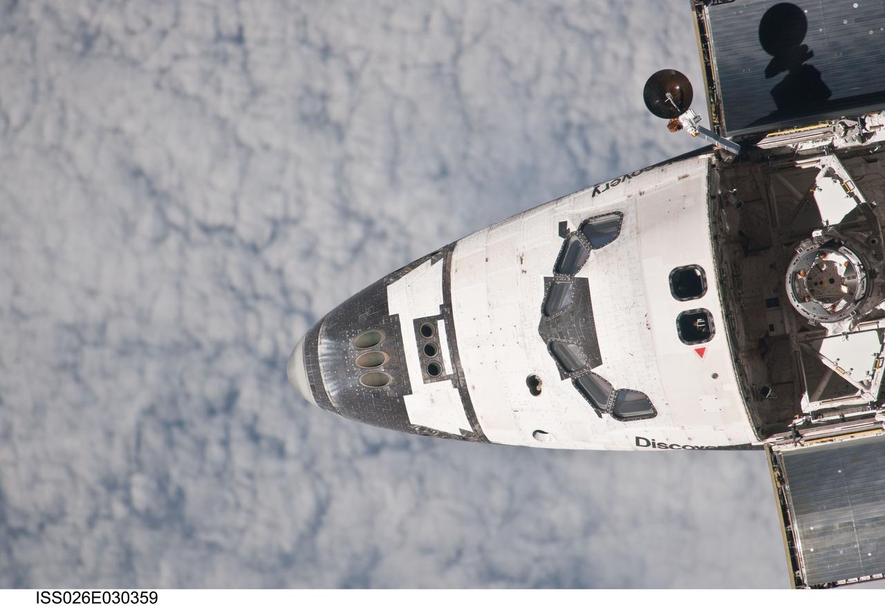 ISS026-E-030359 (26 Feb. 2011) --- This partial view of the nose, crew cabin and forward part of the payload bay of the space shuttle Discovery was provided by an Expedition 26 crew member during a survey of the approaching STS-133 vehicle prior to docking with the International Space Station. As part of the survey and part of every mission's activities, Discovery performed a back-flip for the rendezvous pitch maneuver (RPM).  Discovery’s docking mechanism seen in the cargo bay.  The image was photographed with a digital still camera, using a 1000mm lens.