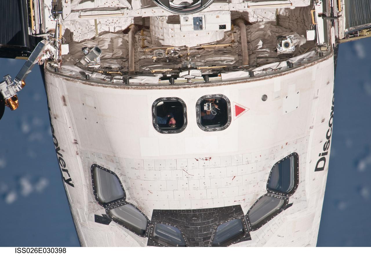 ISS026-E-030398 (26 Feb. 2011) --- This partial view of the  crew cabin of the space shuttle Discovery was provided by an Expedition 26 crew member during a survey of the approaching STS-133 vehicle prior to docking with the International Space Station. As part of the survey and part of every mission's activities, Discovery performed a back-flip for the rendezvous pitch maneuver (RPM). The image was photographed with a digital still camera, using a 1000mm lens.
