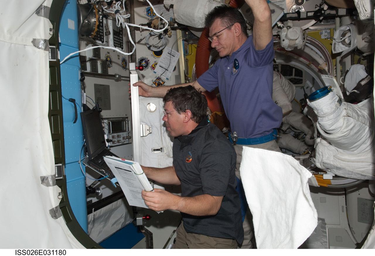 ISS026-E-031180 (28 Feb. 2011) --- NASA astronaut Michael Barratt (left), STS-133 mission specialist; and European Space Agency astronaut Paolo Nespoli, Expedition 26 flight engineer, work in the Quest airlock of the International Space Station while space shuttle Discovery remains docked with the station.