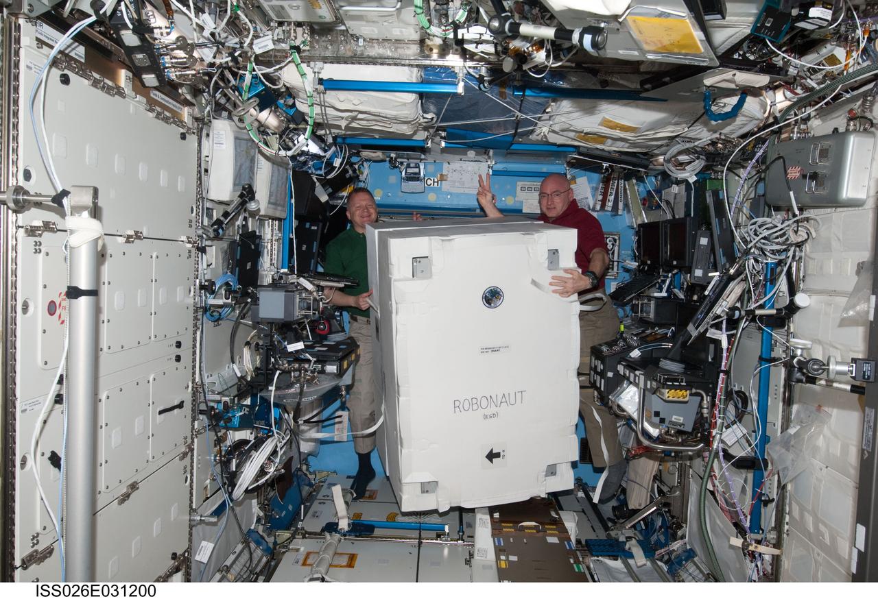 ISS026-E-031200 (2 March 2011) ---  NASA astronauts Eric Boe (left), STS-133 pilot; and Scott Kelly, Expedition 26 commander, move the Robonaut2 container in the Destiny laboratory of the International Space Station while space shuttle Discovery remains docked with the station.