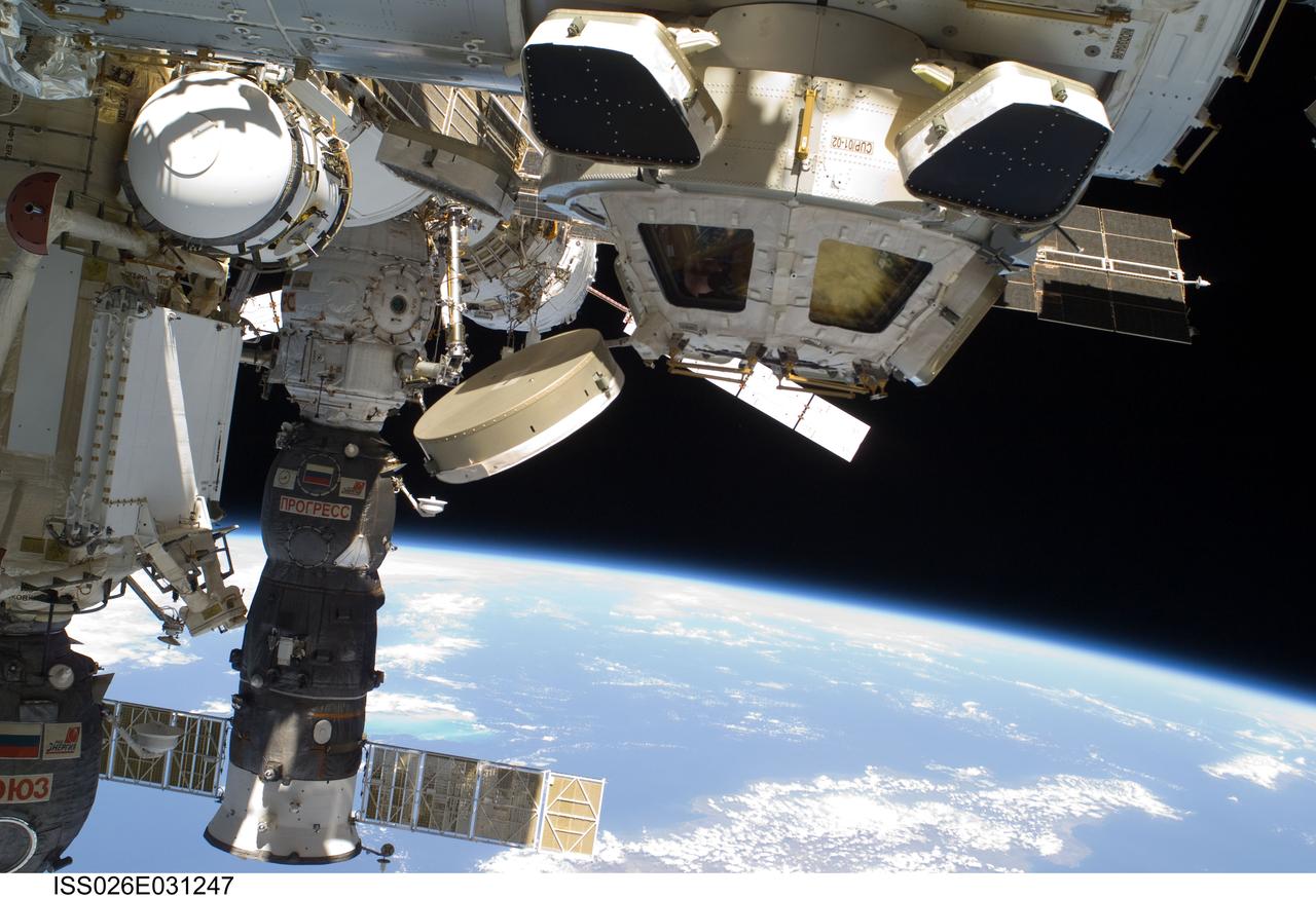 ISS026-E-031247 (2 March 2011) --- Backdropped by Earth?s horizon and the blackness of space, the Cupola of the International Space Station and a docked Russian Progress spacecraft are featured in this image photographed by an Expedition 26 crew member while space shuttle Discovery (STS-133) remains docked with the station.