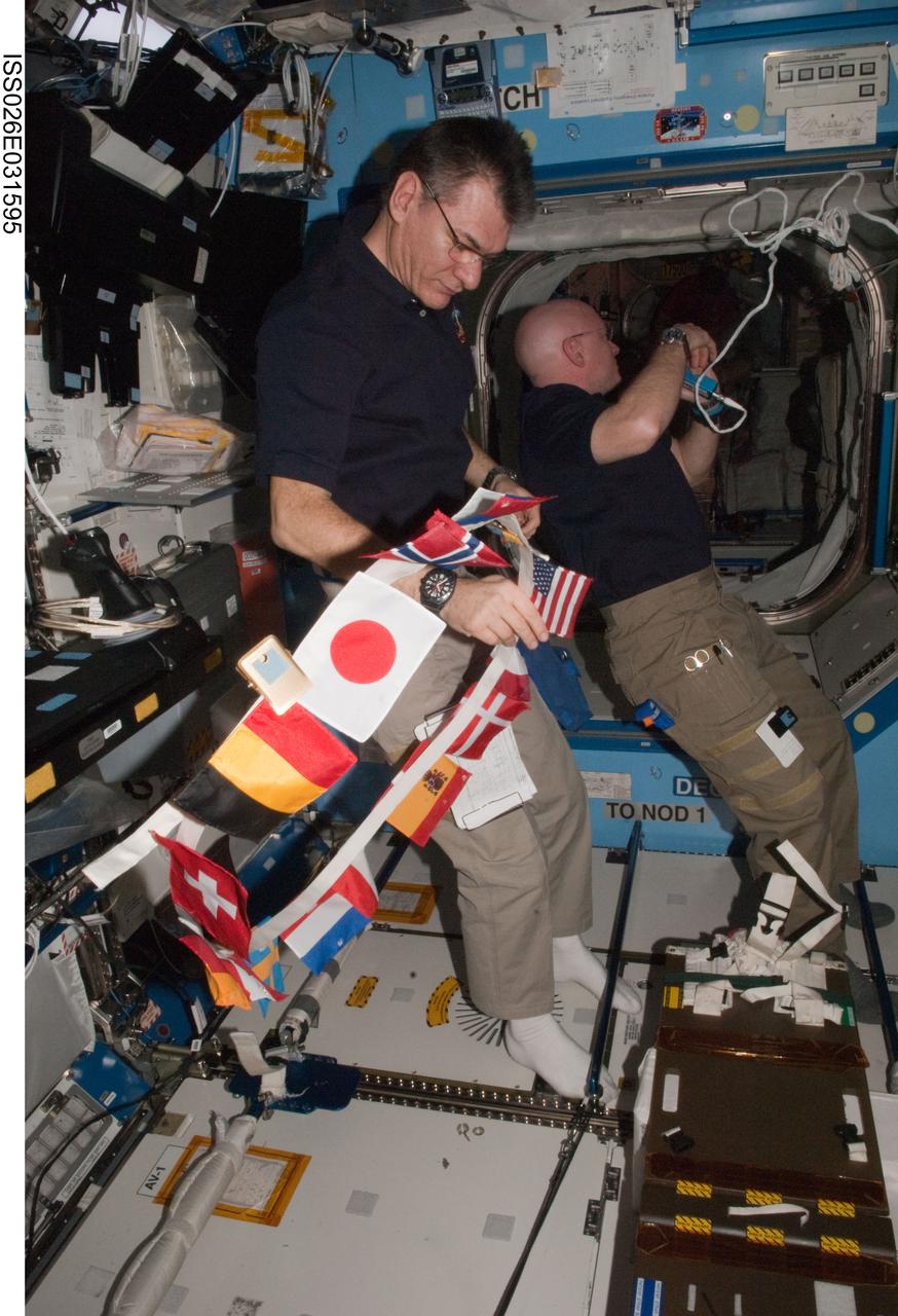 ISS026-E-031595 (3 March 2011) --- Inside the U.S. lab Destiny on the International Space Station, European Space Agency astronaut Paolo Nespoli (foreground) holds a string banner honoring the international partners. NASA astronaut Scott Kelly, Expedition 26 commander, is in the background.