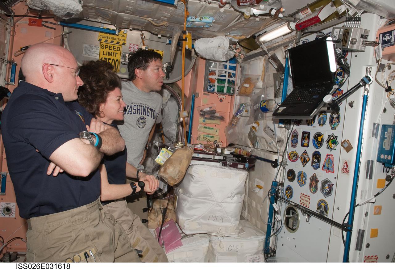 ISS026-E-031618 (3 March 2011) --- NASA astronauts Scott Kelly (foreground), Expedition 26 commander; Cady Coleman, Expedition 26 flight engineer; and Michael Barratt, STS-133 mission specialist, watch a monitor in the Unity node of the International Space Station while space shuttle Discovery remains docked with the station.