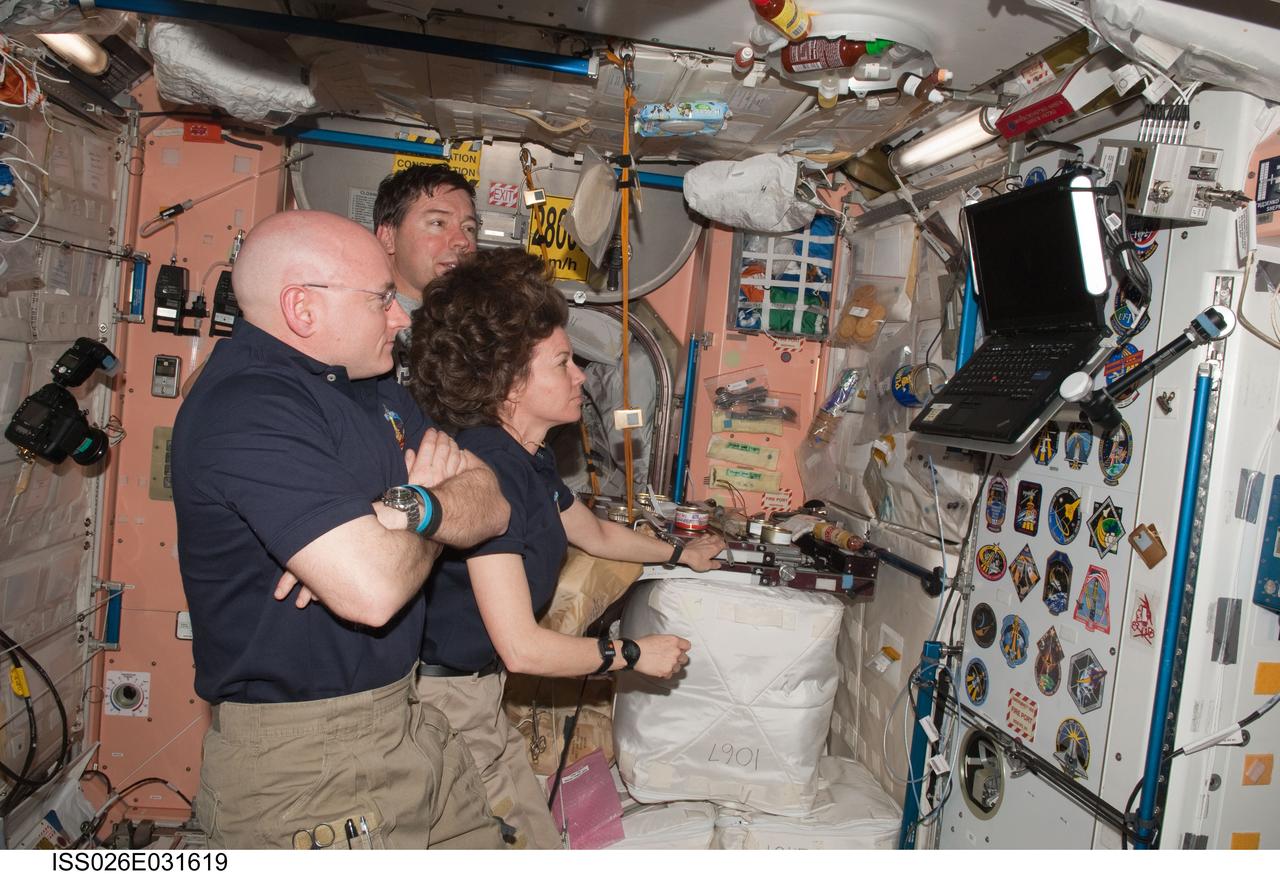 ISS026-E-031619 (3 March 2011) --- NASA astronauts Scott Kelly (foreground), Expedition 26 commander; Cady Coleman, Expedition 26 flight engineer; and Michael Barratt, STS-133 mission specialist, watch a monitor in the Unity node of the International Space Station while space shuttle Discovery remains docked with the station.