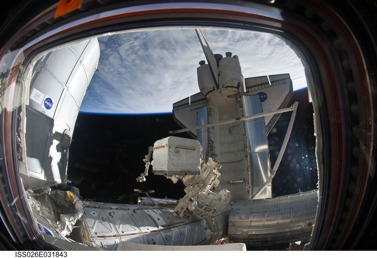 ISS026-E-031843 (2 March 2011) --- An Expedition 26 crew member used a fish-eye lens attached to an electronic still camera to capture this image of the docked space shuttle Discovery (STS-133) and its remote manipulator system/orbiter boom sensor system (RMS/OBSS), the newly-installed Permanent Multipurpose Module (PMM) and the Canadian-built Dextre, also known as the Special Purpose Dextrous Manipulator (SPDM). The blackness of space and Earth's horizon provide the backdrop for the scene.