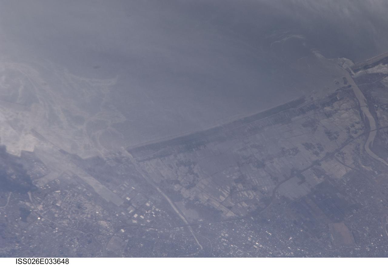 ISS026-E-033648 (13 March 2011) --- From 220 miles above Japan, an Expedition 26 crew member onboard the International Space Station took this 800mm view of Sendai, and the coast mostly north on March 13.  Sunglint helps to highlight the flood waters over the land, flowing out the rivers, plus the heavy oils swirling on the surface with the currents.   An earthquake and subsequent tsunami hit Japan on March 11.
