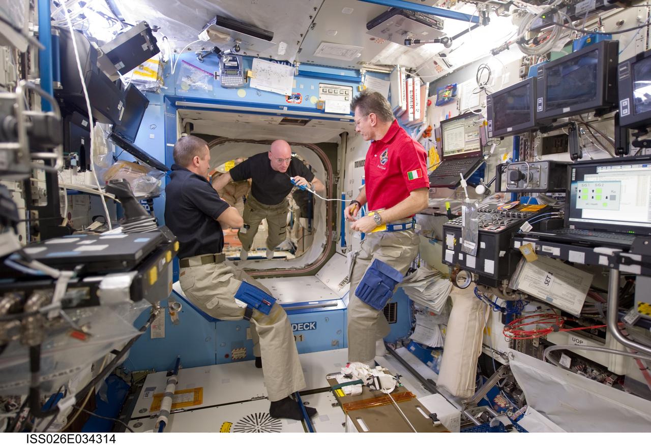 ISS026-E-034314 (15 March 2011) --- Russian cosmonaut Dmitry Kondratyev (left), Expedition 27 commander; NASA astronaut Scott Kelly (center), Expedition 26 commander; and European Space Agency astronaut Paolo Nespoli, Expedition 26/27 flight engineer, are pictured in the Destiny laboratory of the International Space Station.