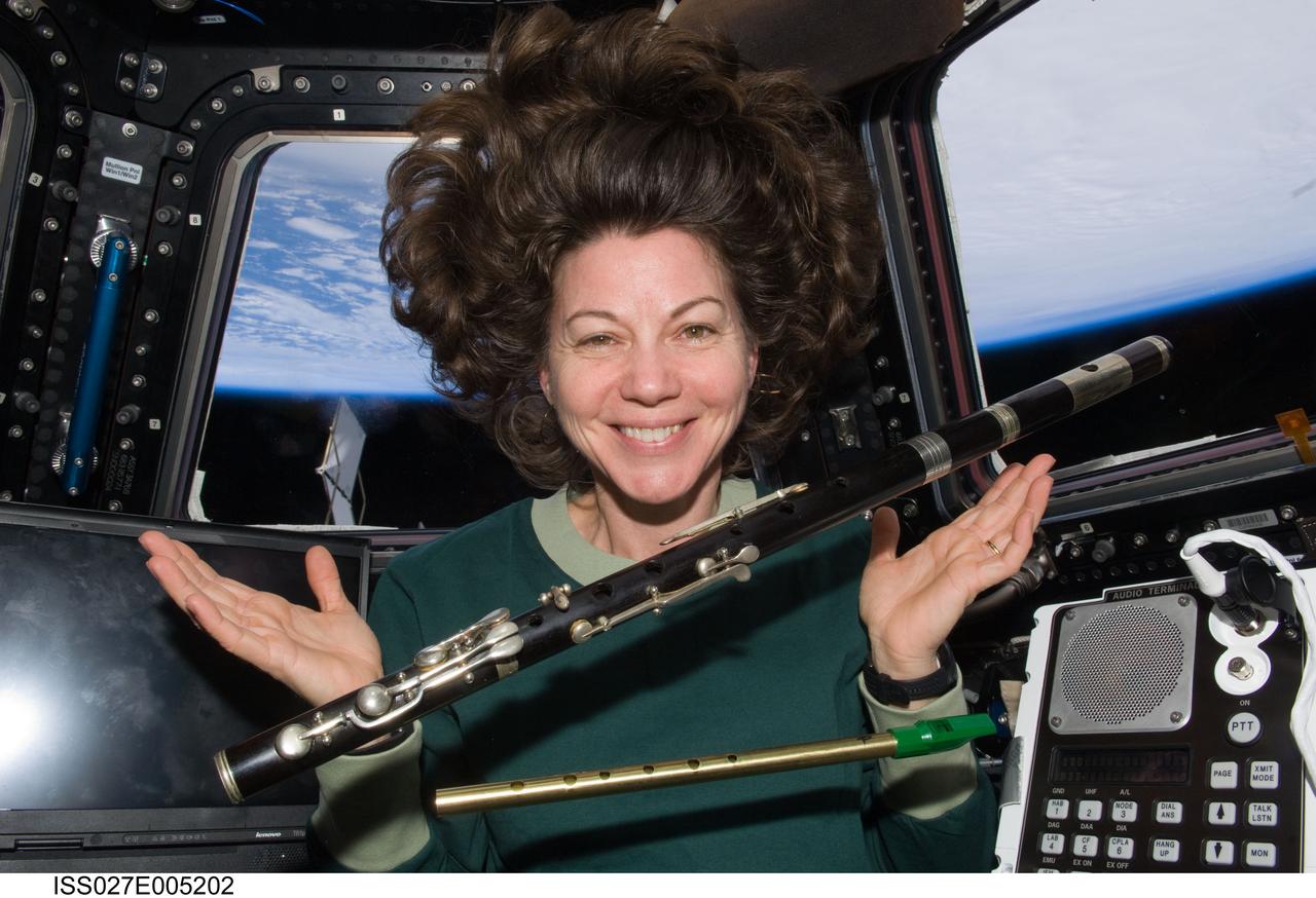 ISS027-E-005202 (16 March 2011) --- Perhaps in keeping with the spirit of the St. Patrick's holiday, astronaut Cady Coleman, ISS-27 flight engineer, looks over two of four flutes brought with her to the International Space Station in her small allotment of personal items. She is in the Cupola.