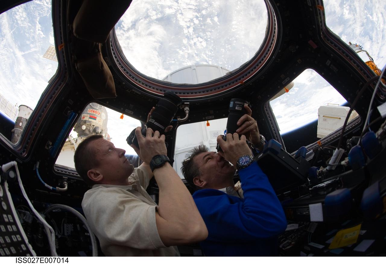 ISS027-E-007014 (19 March 2011) --- Russian cosmonaut Dmitry Kondratyev (left), Expedition 27 commander; and European Space Agency astronaut Paolo Nespoli, flight engineer, use still cameras to photograph the topography of points on Earth from windows in the Cupola of the International Space Station.