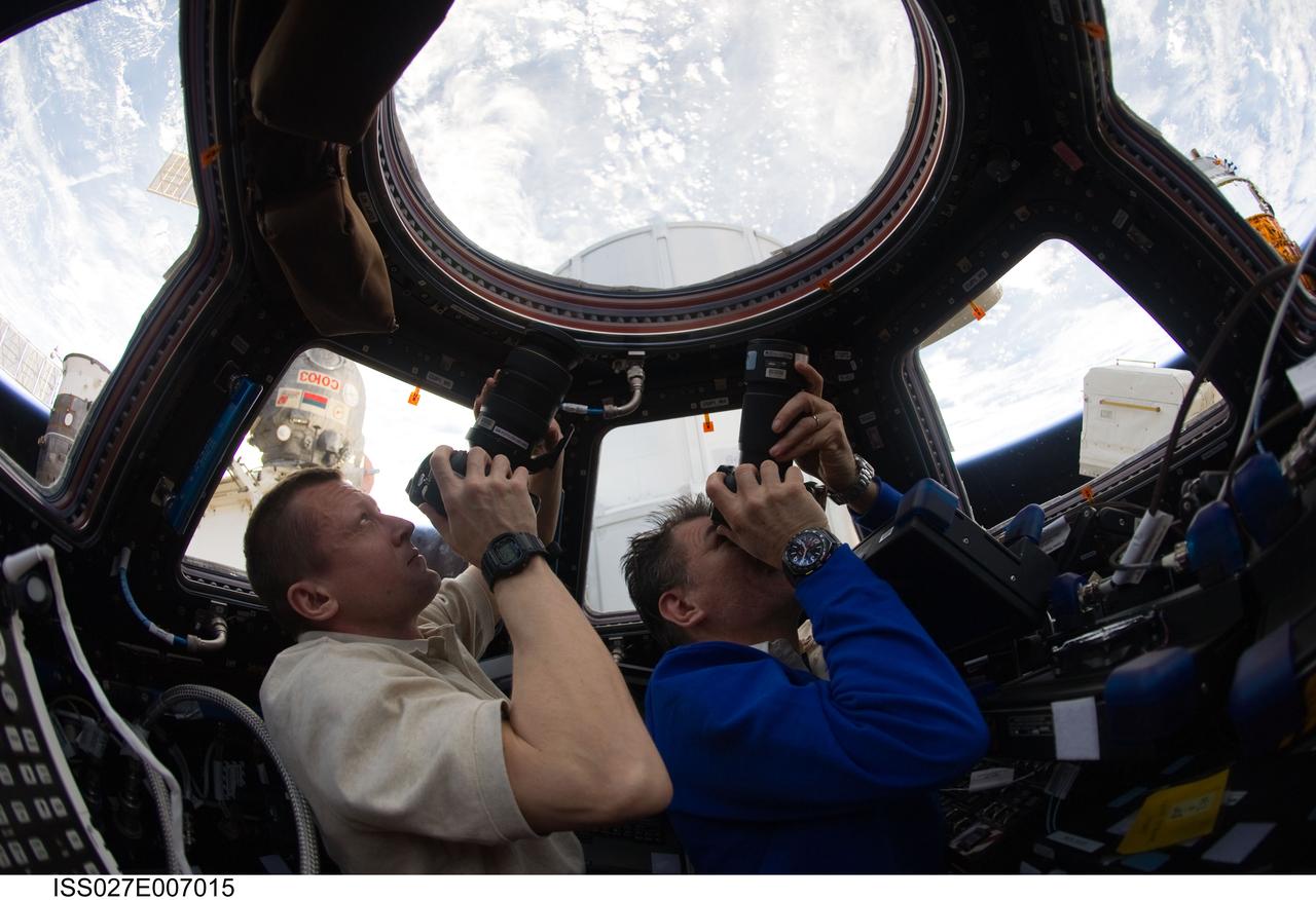 ISS027-E-007015 (19 March 2011) --- Russian cosmonaut Dmitry Kondratyev (left), Expedition 27 commander; and European Space Agency astronaut Paolo Nespoli, flight engineer, use still cameras to photograph the topography of points on Earth from windows in the Cupola of the International Space Station.