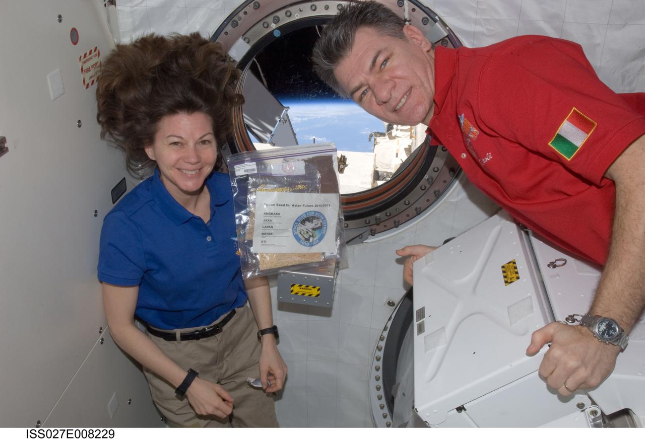 ISS027-E-008229 (26 March 2011) --- NASA astronaut Cady Coleman and European Space Agency astronaut Paolo Nespoli, both Expedition 27 flight engineers, are pictured near a bag of space seeds floating freely in the Kibo laboratory of the International Space Station.