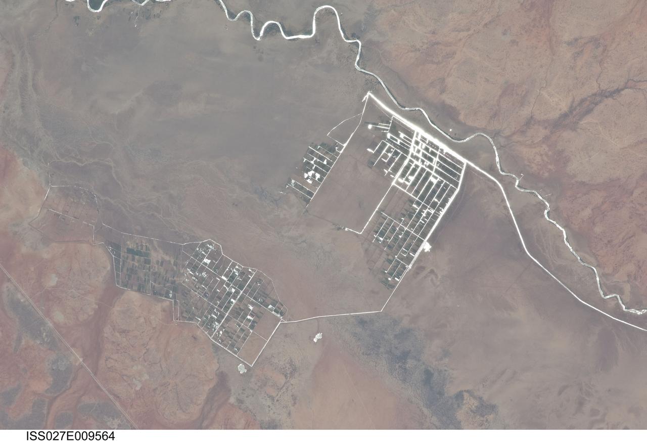 ISS027-E-009564 (31 March 2011) --- Agricultural fields along the Shebelle River in Ethiopia are featured in this image photographed by an Expedition 27 crew member on the International Space Station. The Shebelle River supports limited agricultural development within the arid to semi-arid Ogaden Plateau region of southeastern Ethiopia. This detailed photograph illustrates a network of irrigation canals and fields located approximately 42 kilometers to the west-northwest of the city of Gode, Ethiopia. Floodplain sediments and soils are dark brown to gray (center), and contrast with reddish rocks and soils of the adjacent plateau. Water in the Shebelle River, and the irrigation canals, has a bright, mirror-like appearance due to sunglint, or light reflecting off the water surface back towards the observer on the space station. Vegetation in the floodplain (bottom center) and agricultural fields is dark green. The river water supports a variety of crops?the most common being sorghum and maize?as well as grazing for livestock (cattle, sheep, goats, and camels). The Shebelle River has its headwaters in the Ethiopian Highlands, and transports water and sediment 1,000 kilometers to the southeast across Ethiopia, continuing an additional 130 kilometers into neighboring Somalia. The Shebelle River does not reach the Indian Ocean during most years, but disappears into the sands near the coast in Somalia. During periods of heavy rainfall and flooding however, the Shebelle can reach the Indian Ocean.