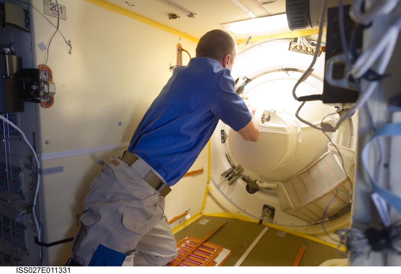 ISS027-E-011331 (6 April 2011) --- Russian cosmonaut Dmitry Kondratyev, Expedition 27 commander, prepares to open the Poisk Mini-Research Module 2 (MRM2) hatch to welcome NASA astronaut Ron Garan, along with Russian cosmonauts Andrey Borisenko and Alexander Samokutyaev, all flight engineers, to the International Space Station. The Soyuz TMA-21 docked to the MRM2 at 7:09 p.m. (EDT) on April 6, 2011.