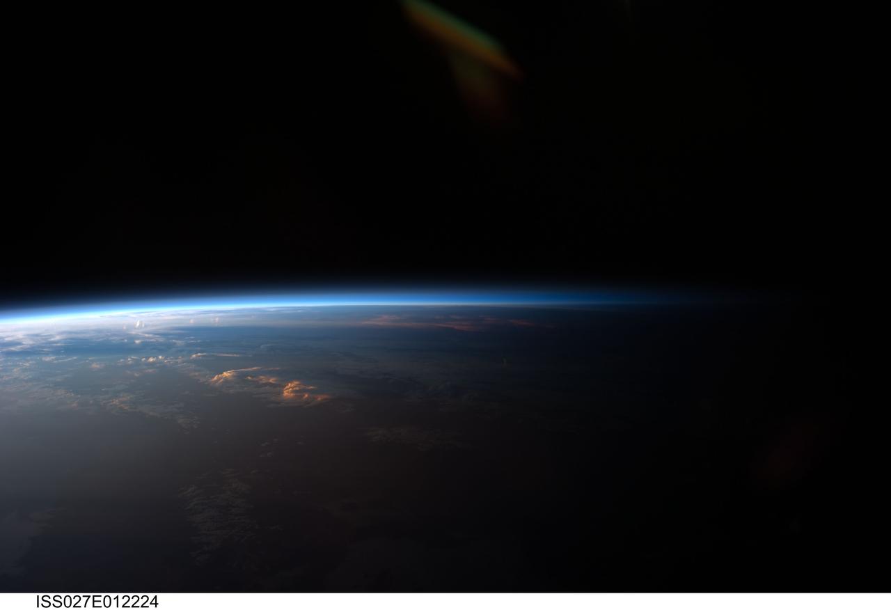 ISS027-E-012224 (12 April 2011) --- Sunset over western South America is featured in this image photographed by an Expedition 27 crew member on the International Space Station. Crew members onboard the space station see, on average, sixteen sunrises and sunsets during a 24-hour orbital period. Each changeover between day and night on the ground is marked by the terminator, or line separating the sunlit side of Earth from the side in darkness. While the terminator is conceptualized as a hard boundary?and is frequently presented as such in graphics and visualizations?in reality the boundary between light and dark is diffuse due to scattering of light by Earth?s atmosphere. This zone of diffuse lighting is experienced as dusk or twilight on the ground ? while the sun is no longer visible, some illumination is still present due to light scattering over the local horizon. The terminator is visible in this photograph trending across the image from lower left to upper right. This panoramic view across central South America, looking towards the northeast, was acquired at approximately 7:37 p.m. local time. Layers of Earth?s atmosphere, colored bright white to deep blue, are visible extending across the horizon (or limb). The highest cloud tops have a reddish glow from the direct light of the setting sun while lower clouds are in twilight. The Salar de Coipasa, a large salt lake in Bolivia, is dimly visible on the night side of the terminator. The salar provides a geographic reference point that allows the location and viewing orientation of the image to be determined.