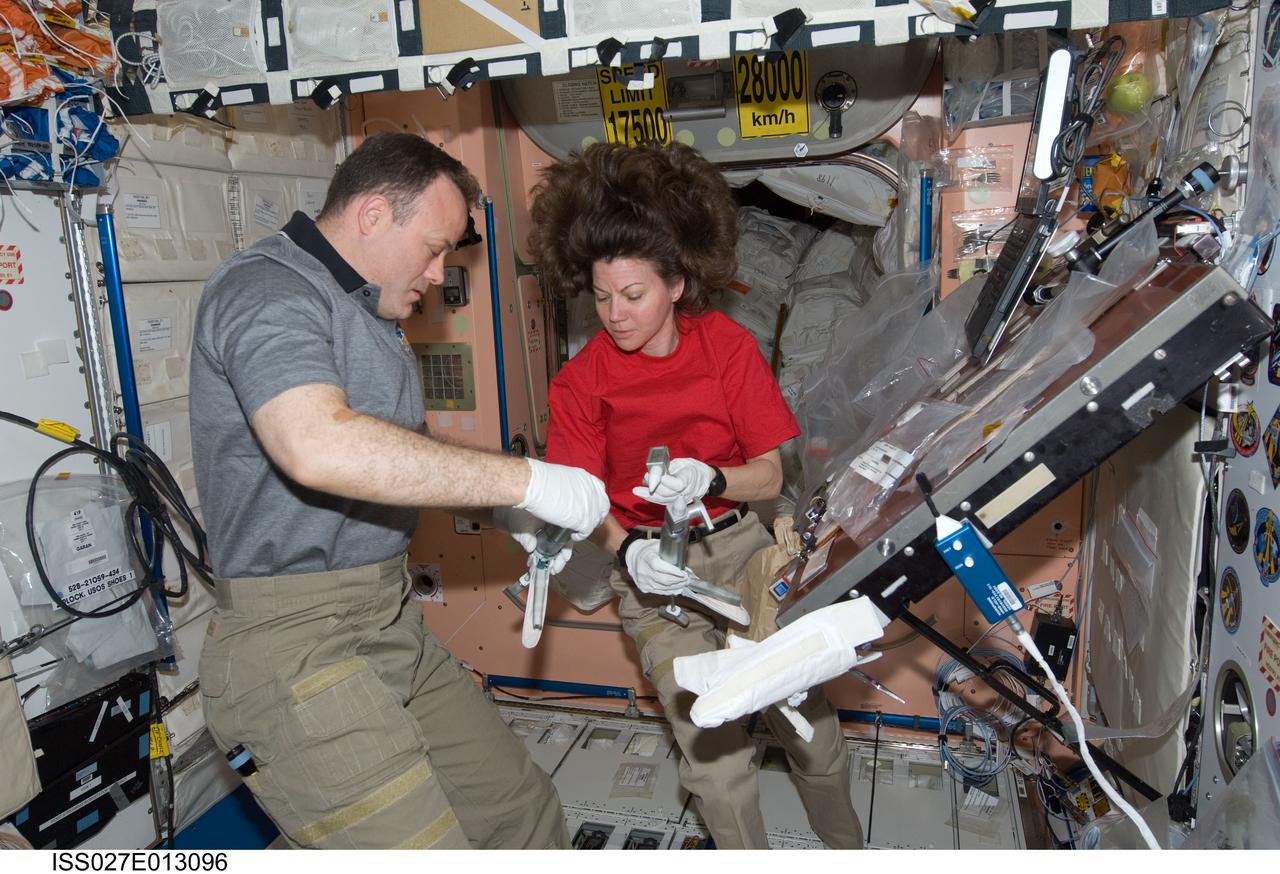 ISS027-E-013096 (15 April 2011) --- NASA astronauts Ron Garan and Cady Coleman, both Expedition 27 flight engineers, work with extravehicular activity (EVA) grease guns in the Unity node of the International Space Station.