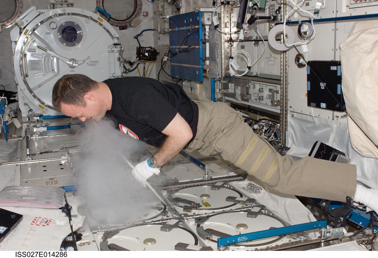 ISS027-E-014286 (14 April 2011) --- NASA astronaut Ron Garan, Expedition 27 flight engineer, replaces a dewar tray containing biological samples in the Minus Eighty Laboratory Freezer for ISS (MELFI-1) in the Kibo laboratory of the International Space Station.