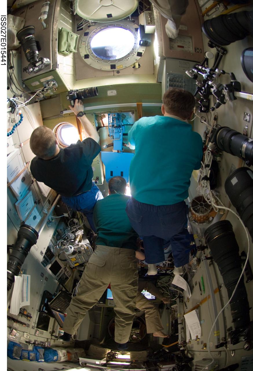 ISS027-E-015441 (22 April 2011) --- Russian cosmonaut Dmitry Kondratyev (left), Expedition 27 commander; along with NASA astronaut Ron Garan (center) and Russian cosmonaut Andrey Borisenko, both flight engineers, watch the departure of the unpiloted ISS Progress 41 supply vehicle through windows in the Zvezda Service Module of the International Space Station.